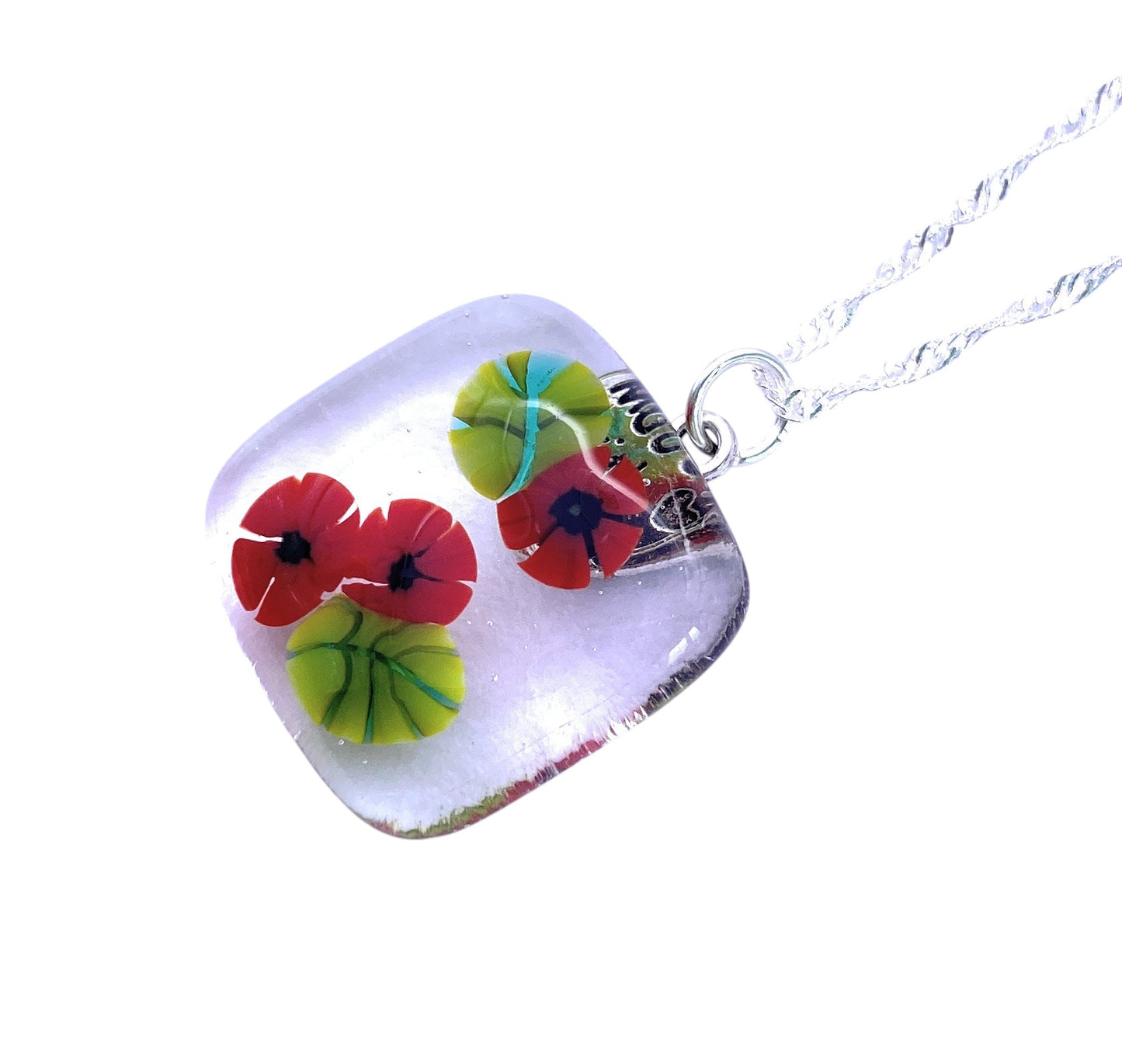 The Calon Glass Poppy Pendant (CGP29) is a handmade square glass flower pendant necklace with red, yellow, and green designs, featuring a silver twisted chain.