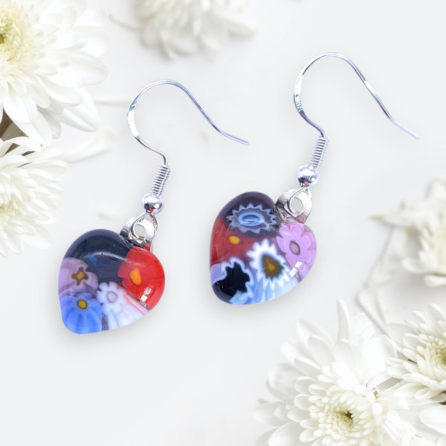 Murano Passion’s Millefiori Glass Flower Earrings—dainty 1.3cm x 1.3cm hearts in vibrant Murano glass with 925 sterling silver—are inspired by Venetian artistry and look stunning displayed among white chrysanthemums.