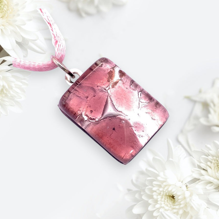 The Murano Passion Murano Glass Pendant on Silver Leaf (Dainty 2cm x 1.5cm, MGPP22) features a pink rectangular design with a pink and white cord, shown among white chrysanthemums. Includes Certificate of Authenticity.