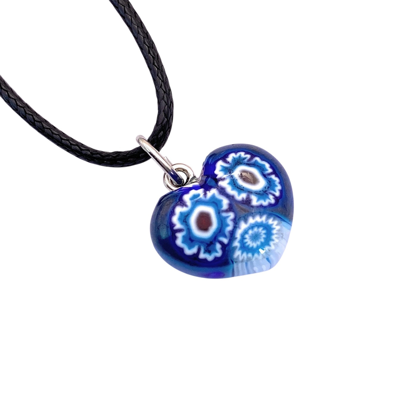 The Murano Passion Murano Glass Heart Pendant (MHT1) features a dark blue base with intricate white and light blue floral patterns, elegantly attached to a black necklace cord. This stunning Millefiori piece is perfect for your collection.