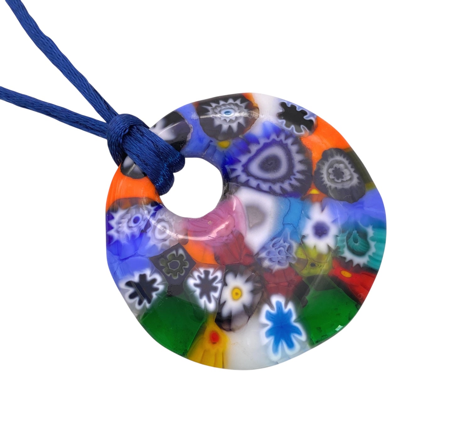 The Murano Passion pendant, a Millefiori masterpiece known as the Murano Glass Pendant - Chunky 4cm in Diameter (MGPV23), showcases vibrant floral and geometric designs in blue, red, orange, green, and white upon its colorful round form with a central hole. It elegantly hangs on a blue cord.