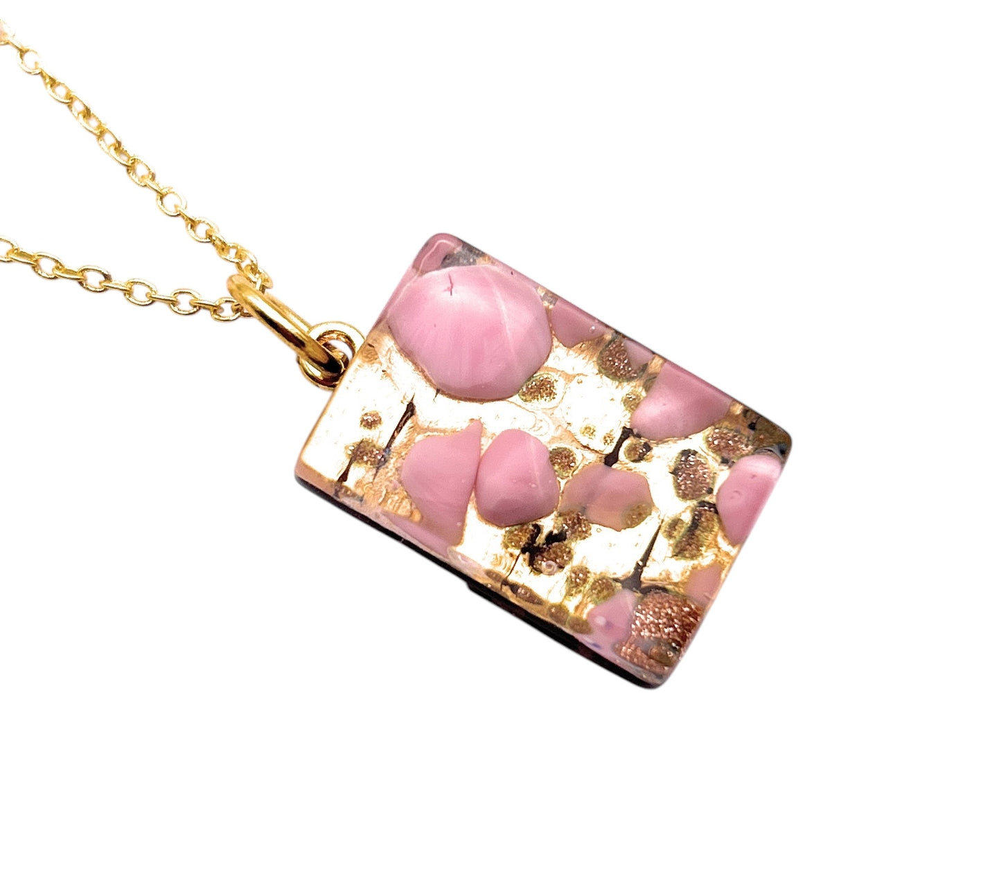 This WEBSITE EXCLUSIVE Murano Passion pendant features pink Millefiori on gold leaf, beautifully embedded in clear resin and reminiscent of Murano Glass Jewellery, elegantly hanging from a gold chain. It's a dainty 2.3cm x 1.5cm rectangular piece.