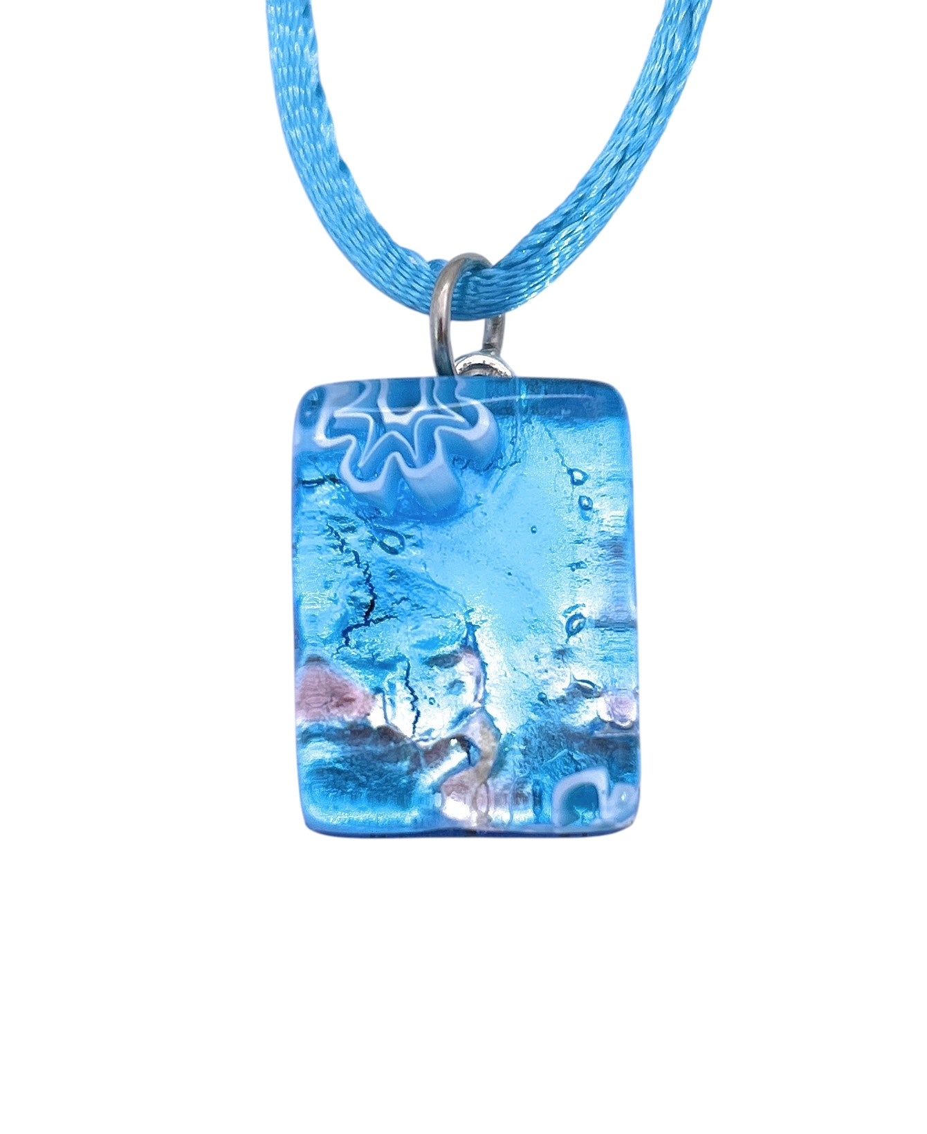 The Murano Passion MGPP18 pendant features a dainty 2cm x 1.5cm blue glass design with swirling patterns and white accents on a blue cord necklace, showcasing Venice's renowned artistry and timeless elegance.