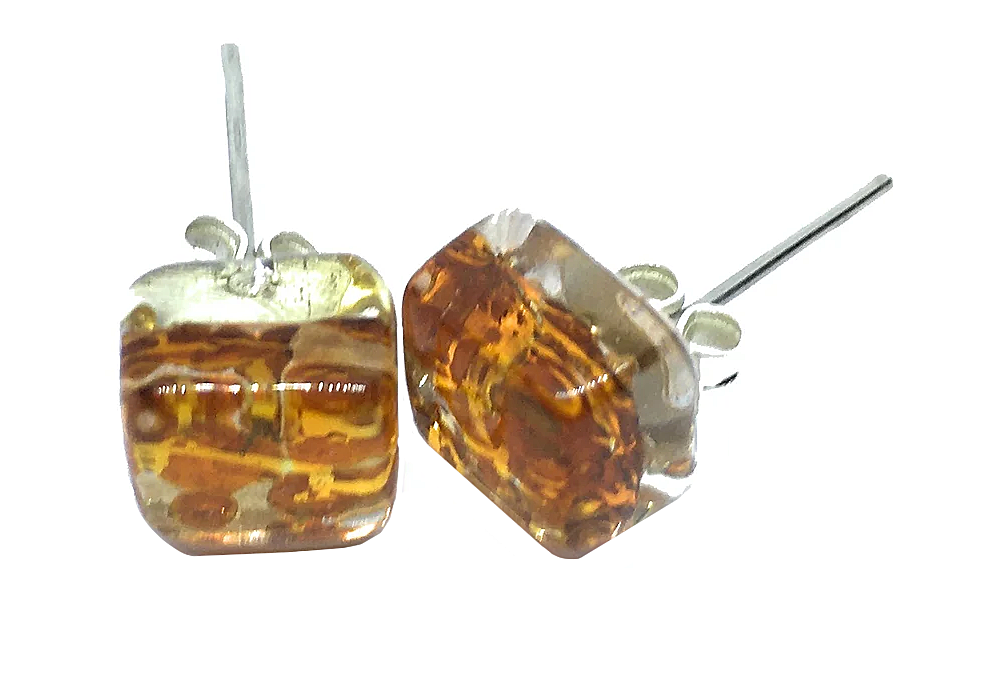 These Murano Passion earrings are a pair of square studs measuring 8mm, showcasing a marbled orange and brown design encased in clear resin. Resembling Murano Glass Jewellery, they come with silver posts and feature small decorative elements on one side.