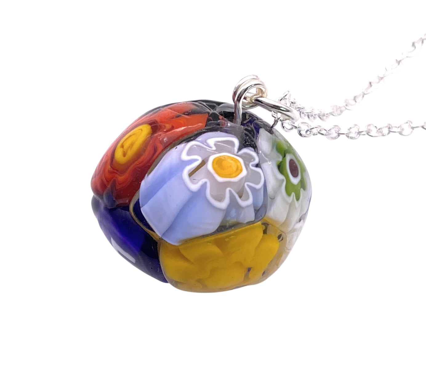 The Murano Glass Multi Coloured Millefiori Ball Pendant (MGB4) by Murano Passion showcases a vibrant array of floral patterns in red, blue, yellow, and green. Crafted from intricate Murano glass, this exquisite jewelry piece is elegantly suspended from a delicate silver chain, perfectly blending artistic flair with sophistication.