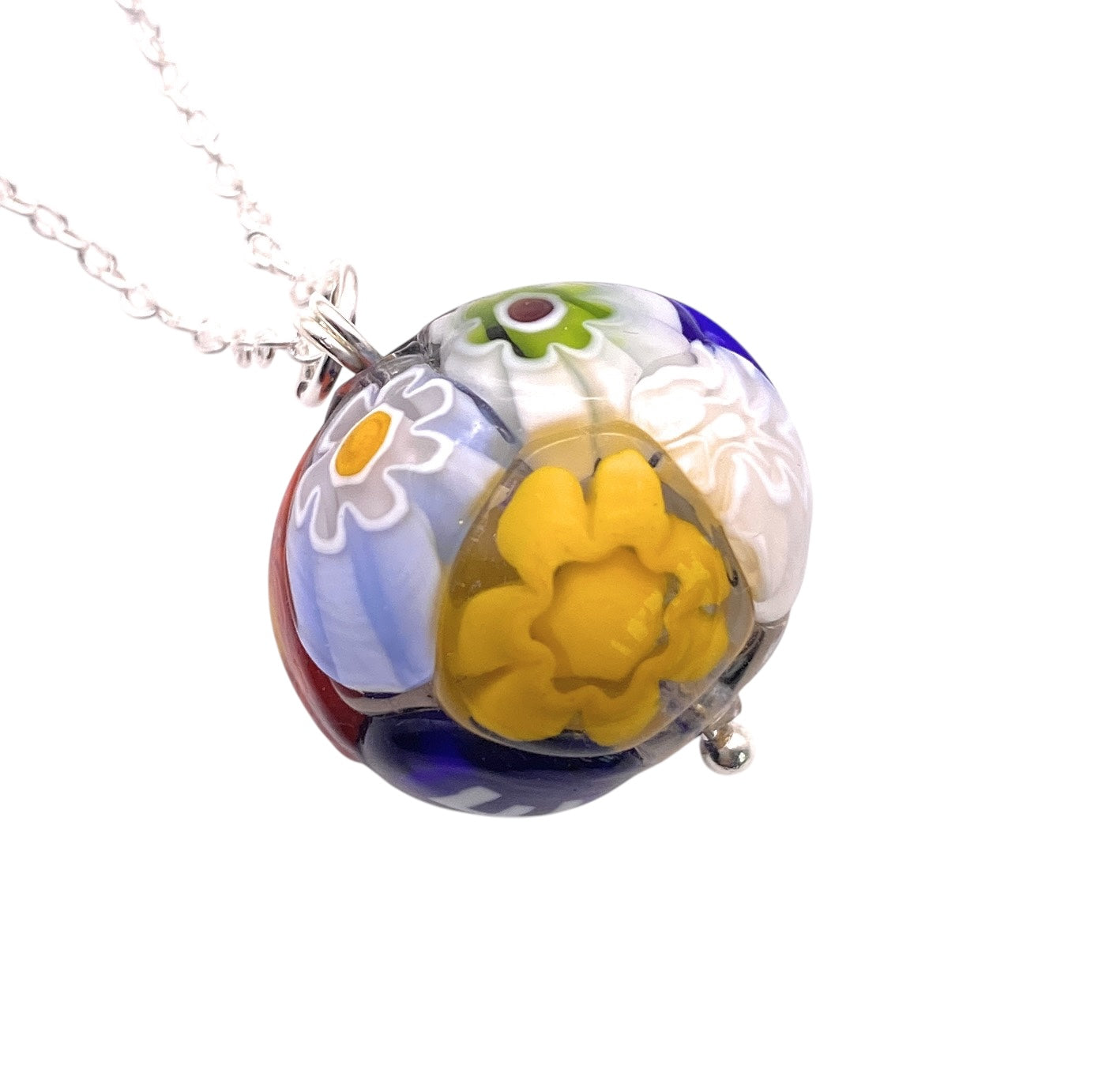 Introducing the Murano Passion "Murano Glass Multi Coloured Millefiori Ball Pendant (MGB4)": a stunning pendant with a silver chain that showcases a colorful floral design. This vibrant piece of Murano glass jewelry features yellow, white, blue, and green flower patterns shimmering within the glass bead.