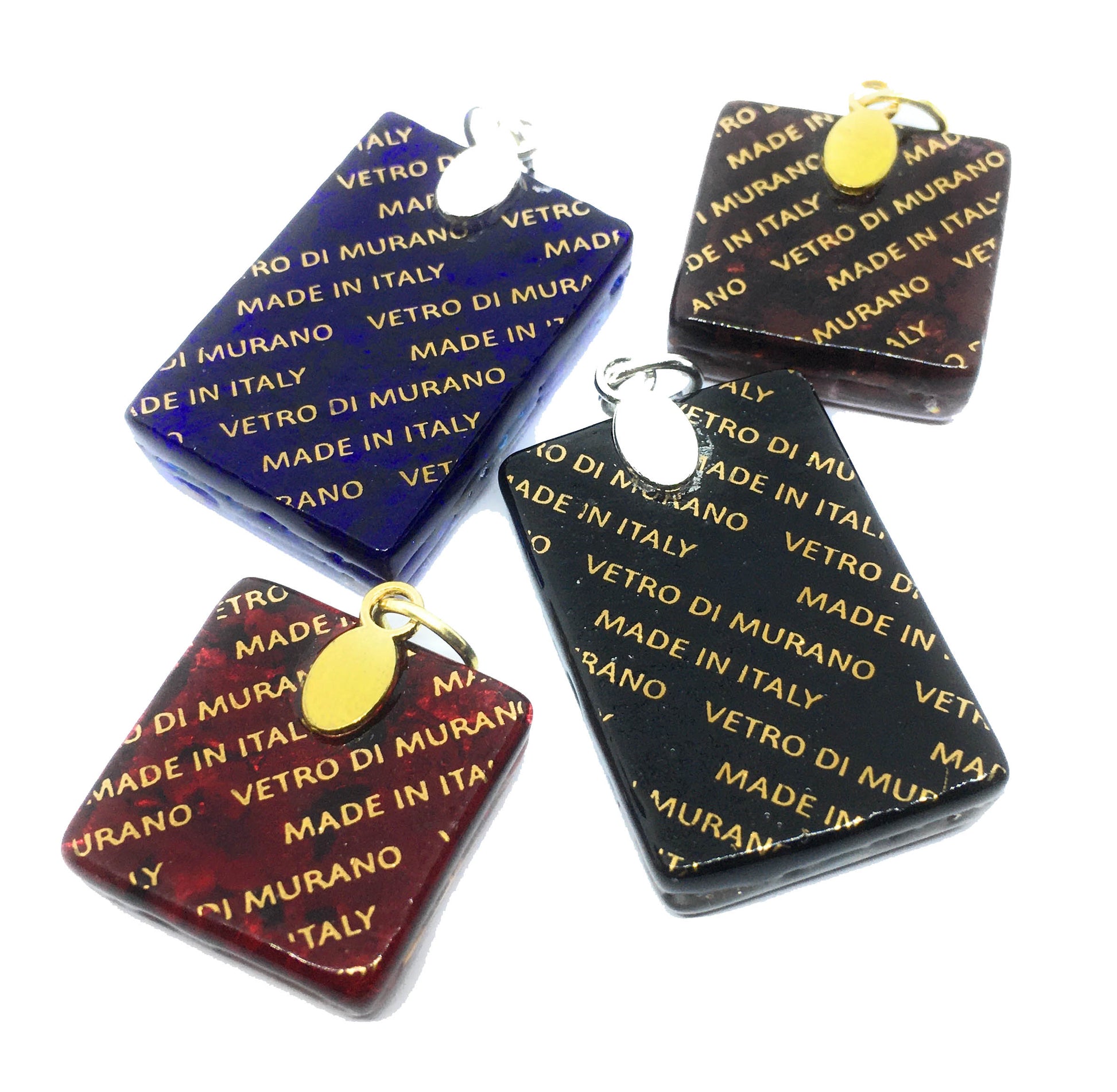 The Murano Passion collection showcases four stunning pendants made of Murano glass in blue, red, brown, and black, each featuring gold metallic inscriptions that state "MADE IN ITALY" and "VETRO DI MURANO." Each elegant piece from the Murano Glass Pendant collection measures 3cm x 2cm and includes a small gold or silver oval charm. They are beautifully displayed against a pristine white backdrop.