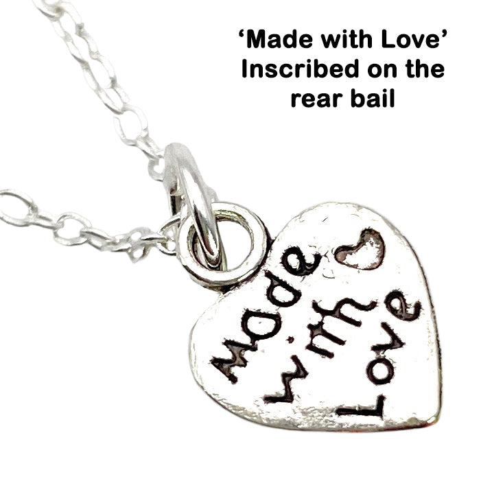 A beautiful heart-shaped pendant from Calon Glass features a delicate design with the inscription "Made with Love" and an elegant small heart engraving, all elegantly hanging on a fine chain. It is presented in a lovely gift box, adding an extra touch of thoughtfulness. Text above the image reads: "'Made with Love' Inscribed on the rear bail.