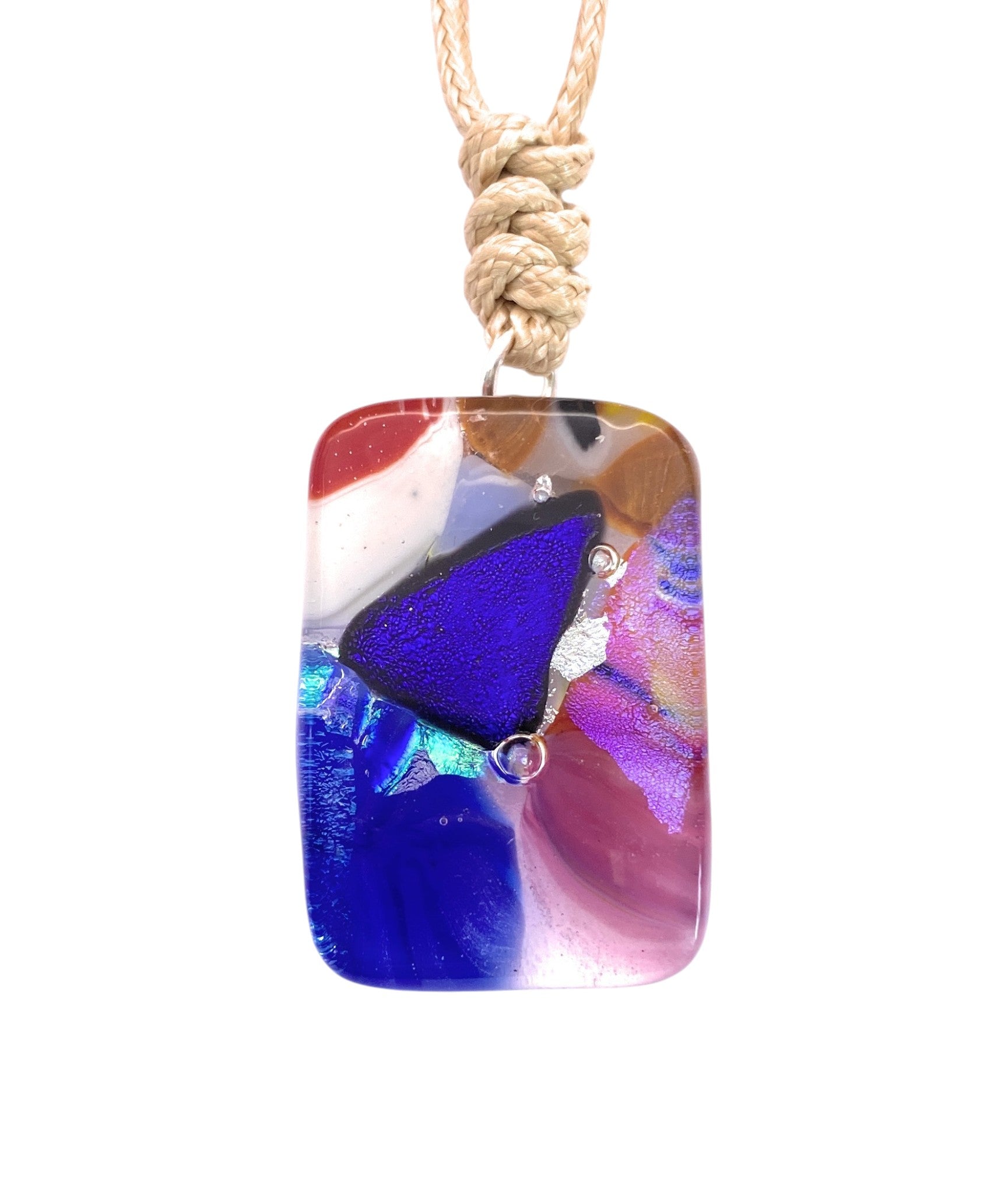 Calon Glass Handmade Dichroic Glass Mosaic Pendant – Multicolour Fused Glass Statement Necklace (CGP83): This striking rectangular glass pendant showcases abstract swirls of blue, purple, pink, red, and white fused within glossy handmade mosaic glass. Featuring a prominent blue triangle at its center, the pendant is suspended from a tan braided cord for a unique statement look.