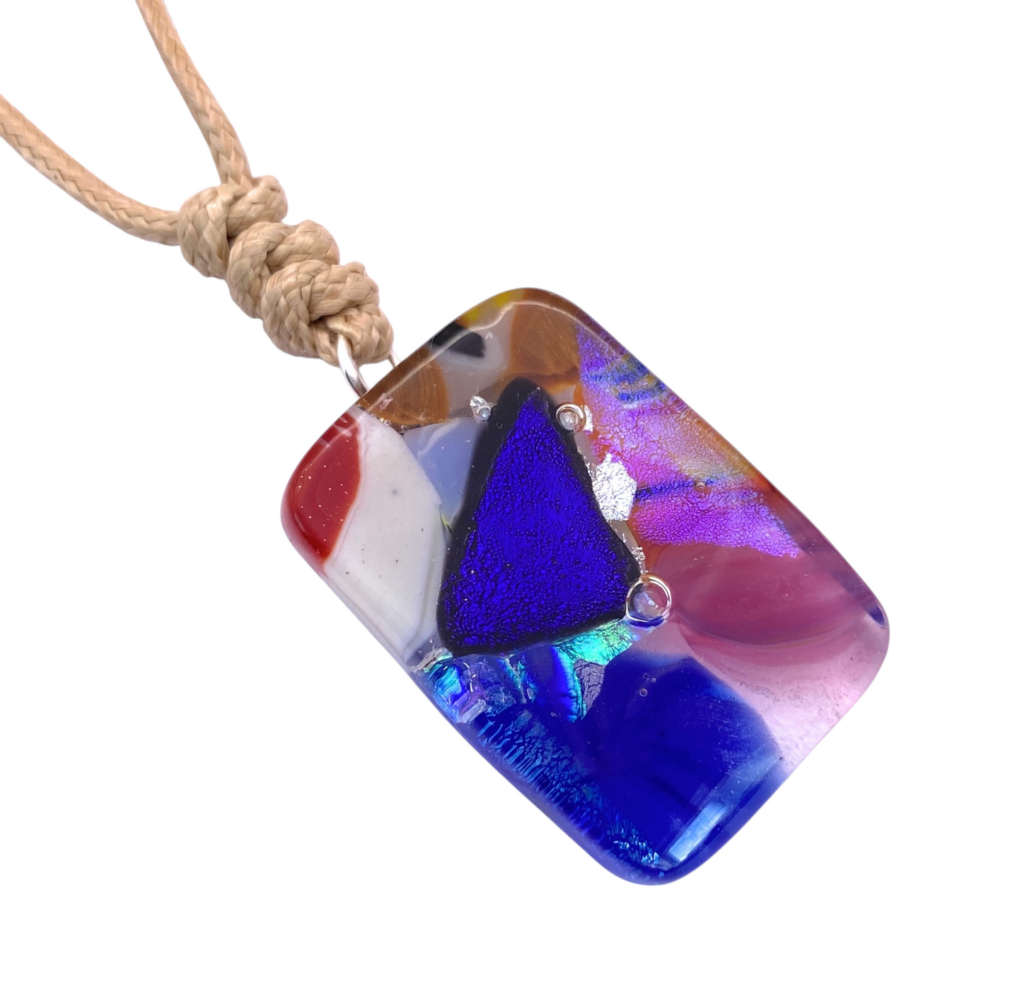 Introducing the Calon Glass Handmade Dichroic Glass Mosaic Pendant – Multicolour Fused Glass Statement Necklace (CGP83): a rectangular fused glass jewellery pendant featuring vibrant abstract patterns and a striking large blue triangle, elegantly suspended from a beige cord with a knotted loop. This unique necklace is a stunning example of handmade mosaic glass artistry.