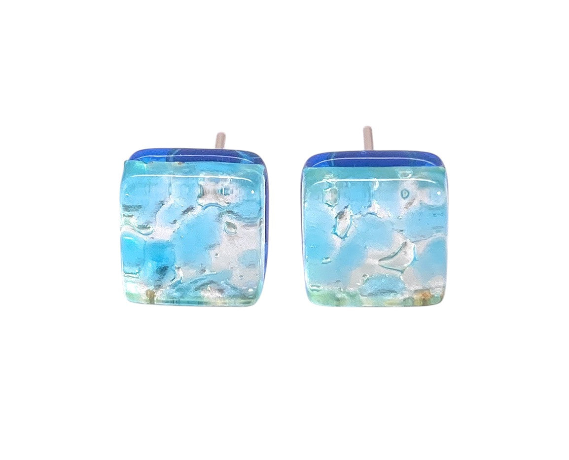 Murano Passion’s Murano Glass Earrings (MGE18) feature a dainty 8mm square design in pale blue and silver, with marbled textures and hints of green and white—a refined showcase of authentic Murano glass craftsmanship.
