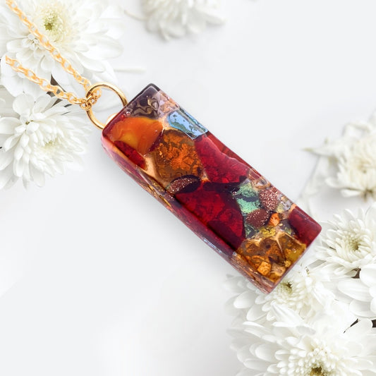 The Murano Passion Murano Glass Pendant (3cm x 1cm, Gold Leaf) hangs on a gold chain, surrounded by white chrysanthemums against a light background.