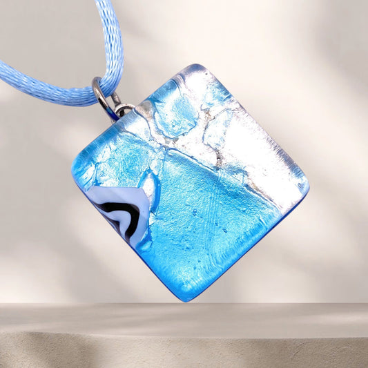 A square blue and silver Murano Glass Pendant, Blue on Silver Leaf, 2cm x 2cm (MGPD12) on a light blue cord.