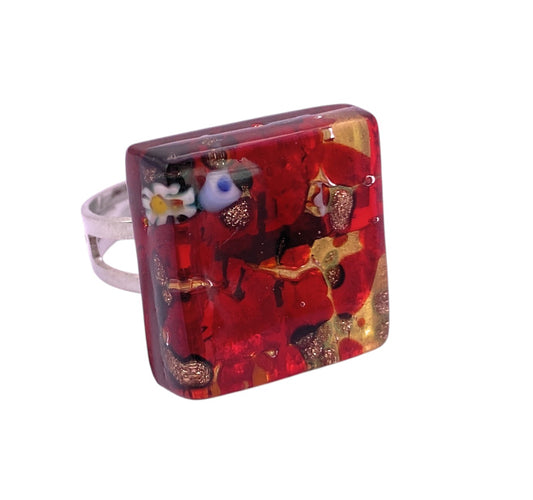 The Murano Passion Murano Glass Ring (MGR1) features a 2cm x 2cm square red top with gold leaf, vibrant millefiori floral designs, and a silver band—handcrafted in Venice for a unique, colorful look.