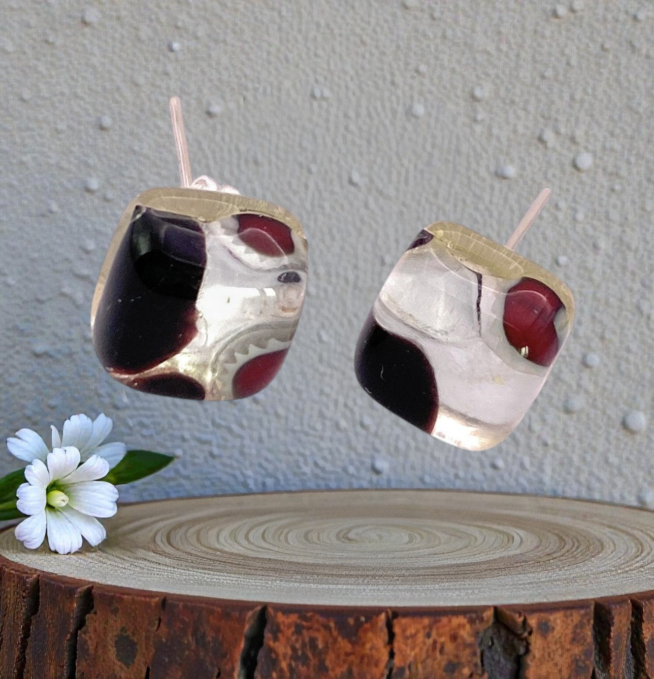 Murano Passion’s Murano Glass Earrings - Multi on Silver, Dainty 8mm (MGE3) feature elegant black and red details inspired by Venetian jewelry, shown on wood beside a white flower with green leaves against a light textured backdrop.
