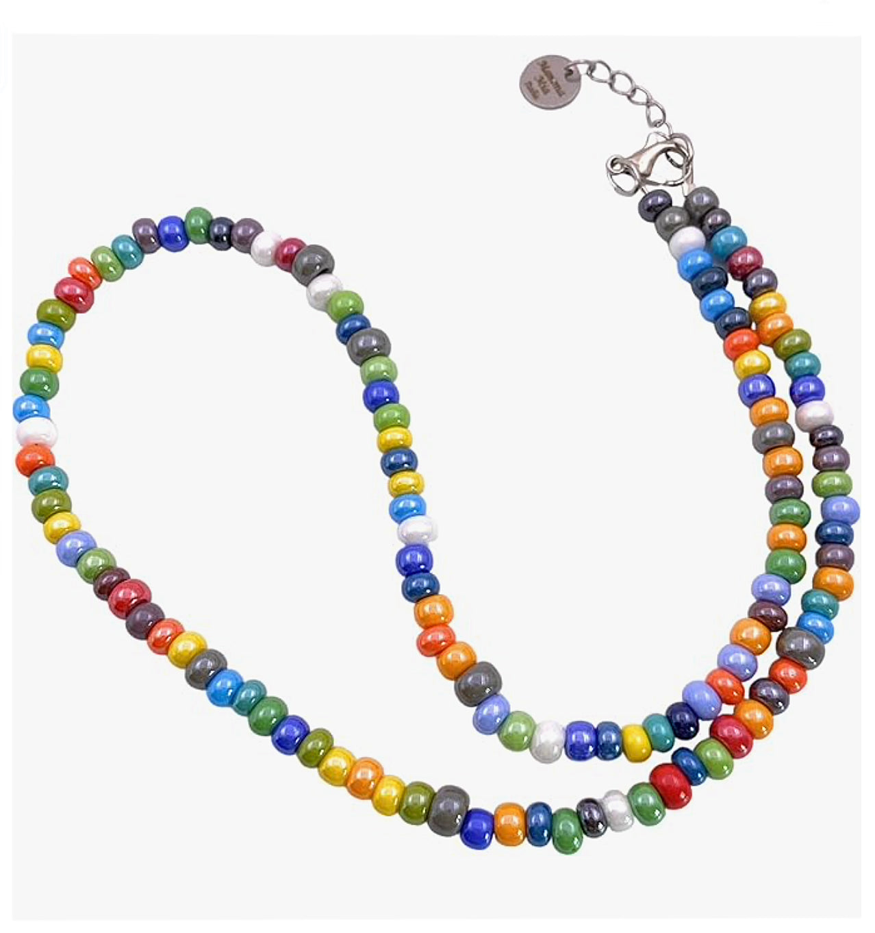 The Murano Glass Beaded Necklace by Murano Passion, also known as the Multi-Coloured Rainbow Necklace (MGNL1), showcases dainty 5mm Murano glass beads in vibrant hues such as red, blue, green, orange, and yellow. This exquisite Venetian jewelry features a metal clasp and an adjustable chain for a perfect fit.