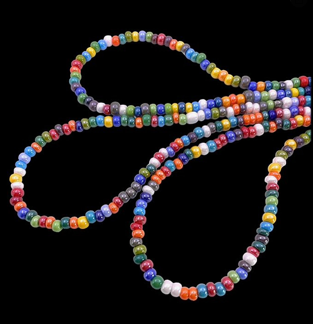 Intertwined against a black background, the Murano Passion's Murano Glass Beaded Necklace showcases a vivid array of colors. Featuring dainty 5mm beads, this multi-coloured rainbow necklace highlights a lively pattern with stunning shades of red, blue, green, yellow, and purple.