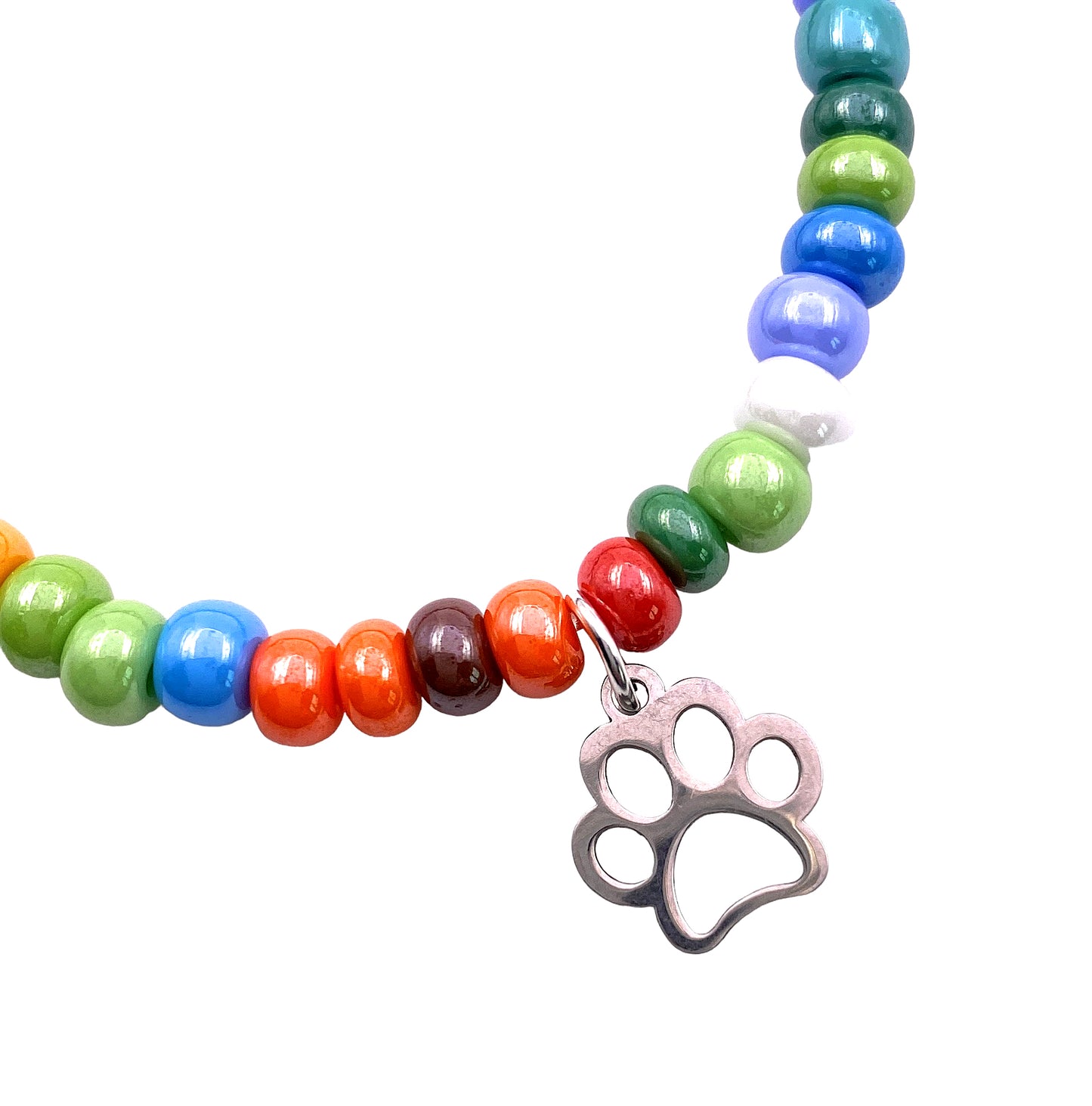 Introducing the Murano Passion Murano Glass Beaded Bracelet with Paw Print Charm, featuring dainty 5mm multi-coloured beads in green, blue, orange, and red tones. This elasticated bracelet (MGBR6) showcases a charming silver paw print charm against a white background, emphasizing the exquisite craftsmanship of this handmade jewelry piece.