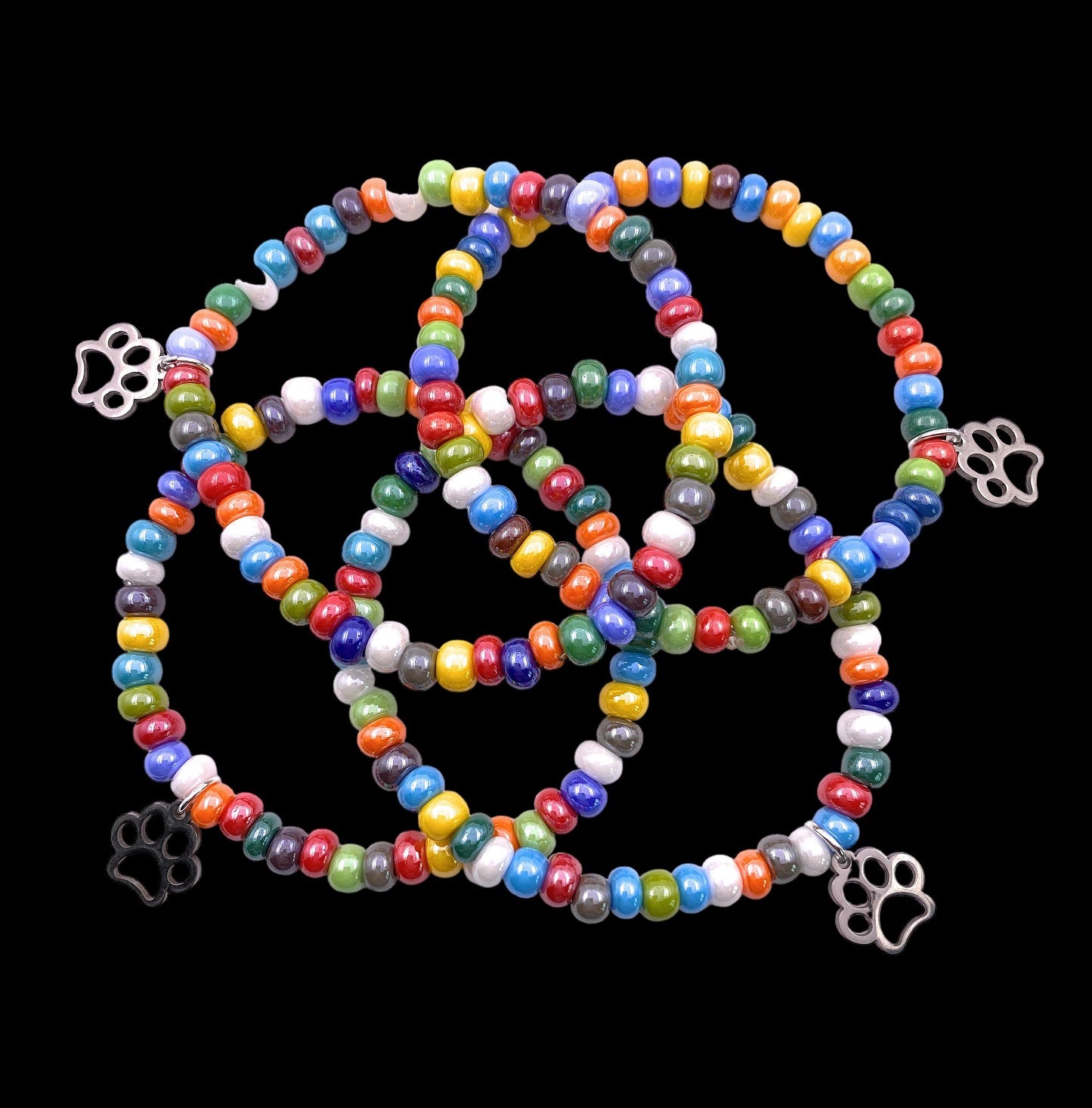 Murano Passion's MGBR6 bracelet features dainty 5mm multi-colored beads made from genuine Murano glass, complete with metal paw print charms, all set against a black background with an elasticated design.