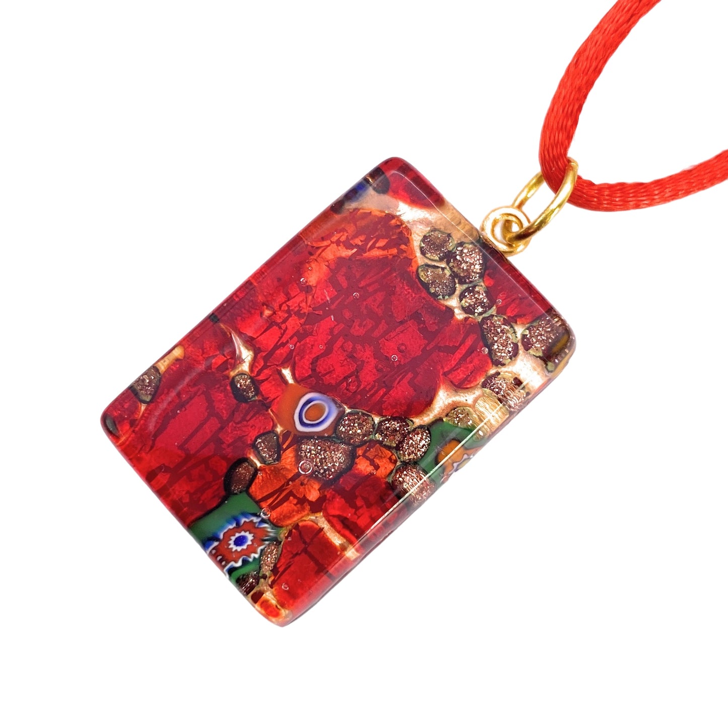 A Murano Passion Glass Pendant made with Millefiori, measuring 3cm by 2cm, showcases vibrant red and orange mosaic patterns accented with a touch of green. It hangs elegantly from a red cord and features metallic and decorative elements that provide a textured, artistic appearance. This exquisite piece includes a Certificate of Authenticity.