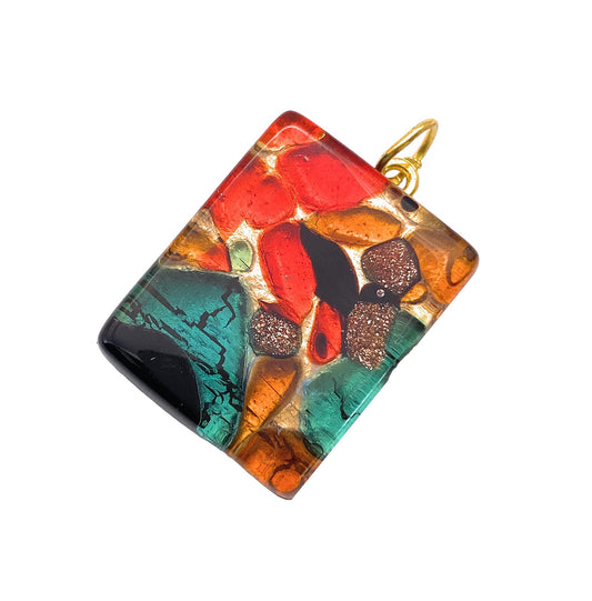 A vibrant Murano Glass Pendant on Gold Leaf from Murano Passion, measuring 2.5cm x 2cm, showcases an abstract mosaic design with red, green, orange, black, and metallic elements and is completed with a yellow-gold loop. Handmade in Italy.