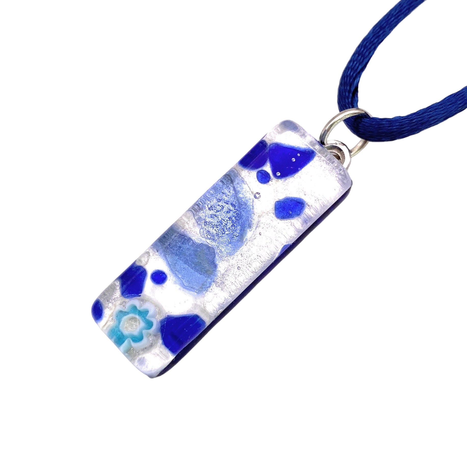 The Murano Passion MGPL4 Pendant on Silver Leaf features a rectangular glass design with a striking blue and white abstract pattern, elegantly suspended on a dark blue cord. With its artistic shapes and delicate flower motif, this piece exemplifies the exquisite craftsmanship synonymous with Murano Glass Jewellery.