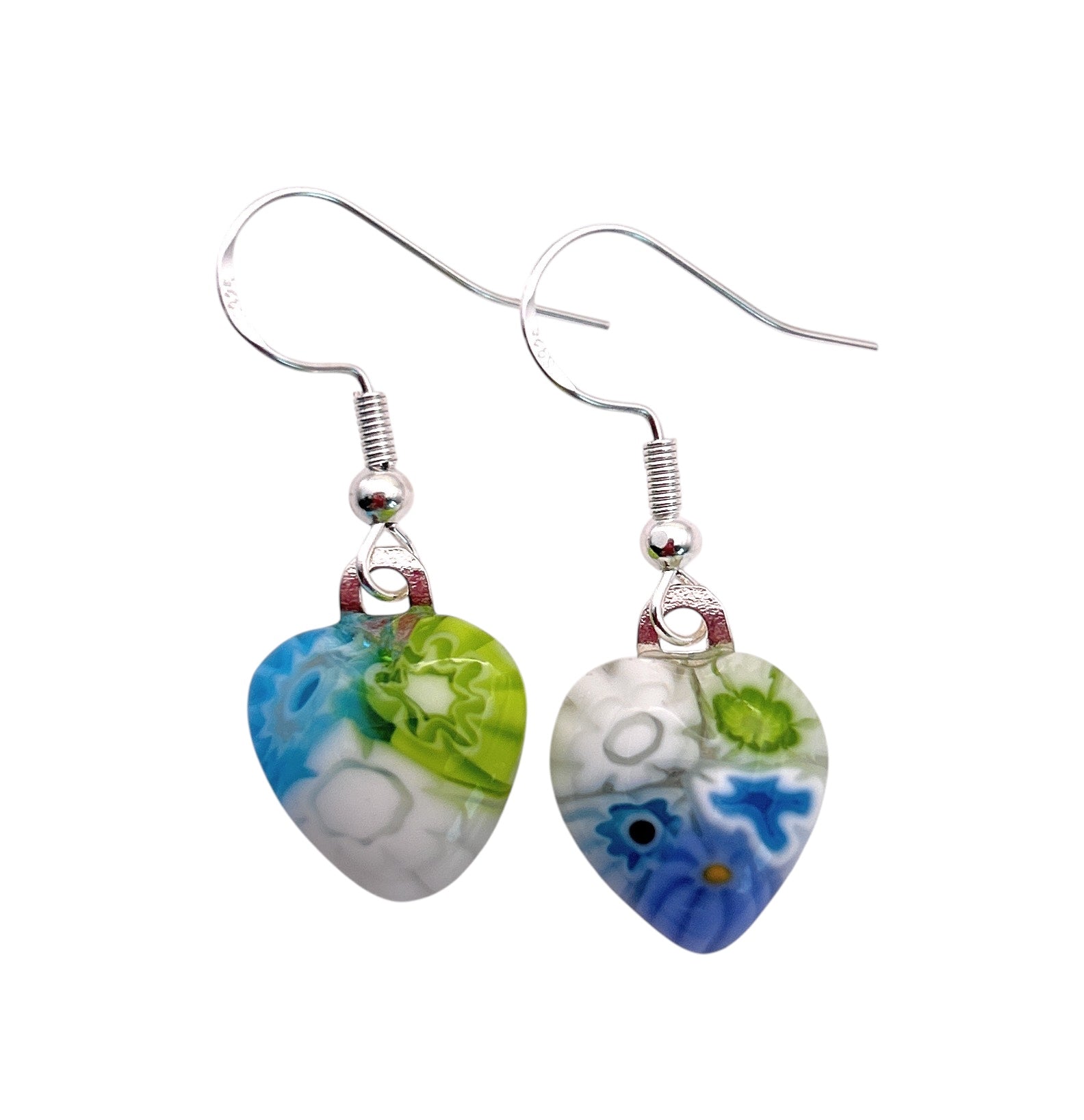 Heart-shaped earrings with a colorful floral design, featuring blue, green, and white patterns, hang from simple sterling silver hooks. The intricate details create a vibrant look against a plain background.