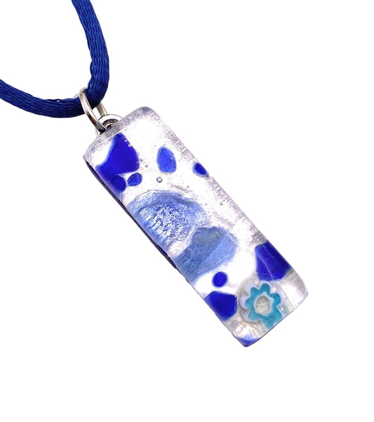 The Murano Passion MGPL4 pendant is a rectangular piece of Murano glass mounted on a silver bail, showcasing abstract blue and white patterns with swirls and a floral motif. It hangs from a blue cord, presenting a contemporary artistic flair. Each pendant includes a Certificate of Authenticity.