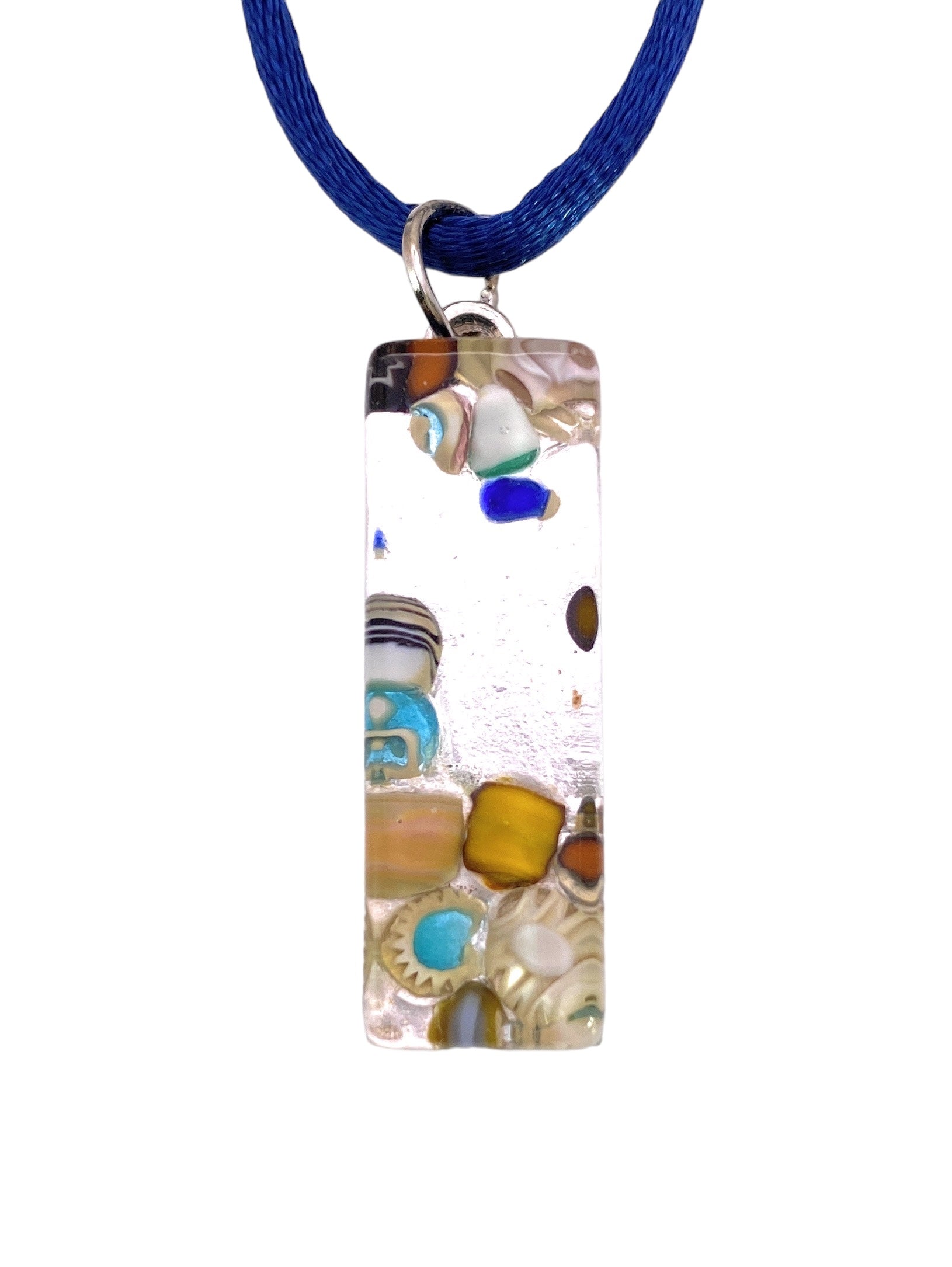 Introducing the Murano Passion Murano Glass Pendant on Silver Leaf (MGPL10), measuring 3cm x 1cm. This rectangular piece showcases a dazzling display of colorful embedded beads and patterns, attached to a blue cord necklace. Featuring an array of shades in blue, brown, and turquoise, it boasts a stunning artistic, mosaic-like appearance. Each pendant is accompanied by a Certificate of Authenticity.