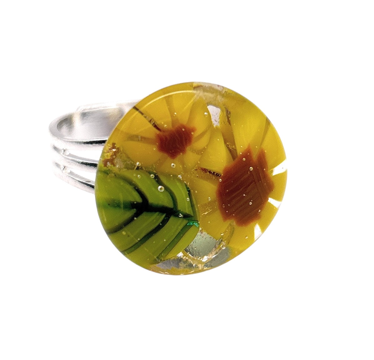 The Sunflower Ring by Calon Glass features a vibrant millefiori top, displaying yellow and red flowers entwined with green leaves, all set on an elegant silver band. This Flower Ring is meticulously crafted from handmade glass.