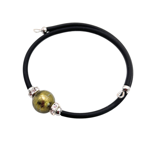 The Murano Passion Murano Glass Bead Bracelet boasts a striking black band adorned with a central 1cm metallic green Murano Glass bead and elegant silver accents. The sleek design is enhanced by decorative silver elements near the clasp, exuding elegance and sophistication.