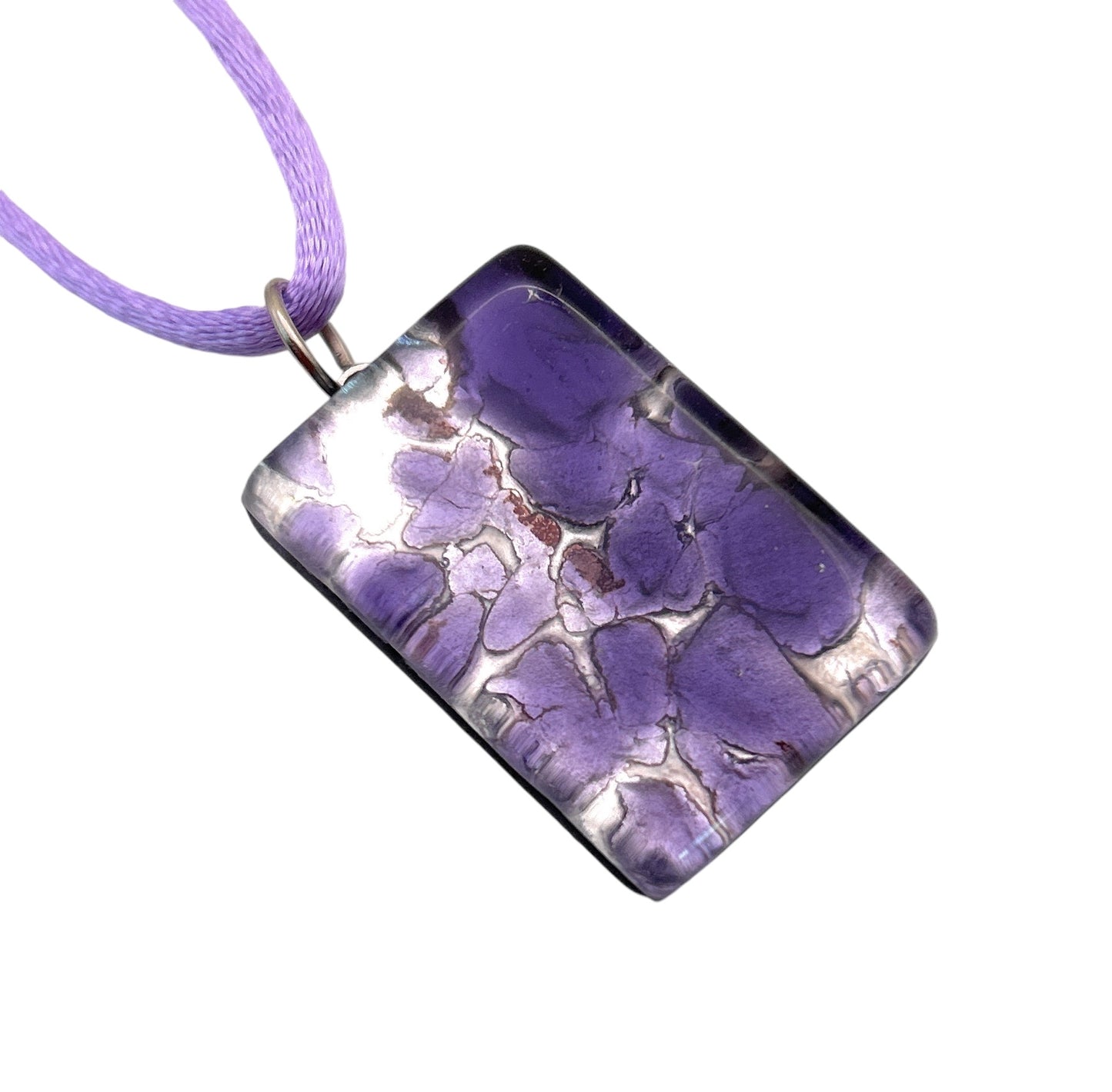 The Murano Passion Millefiori Flower Pendant on Silver Leaf, measuring 3cm by 2cm (MGPC2), showcases a marbled purple pattern and glossy finish. Elegantly suspended on a light purple cord necklace, this exquisite piece of Italian jewelry is crafted with precision and comes with a Certificate of Authenticity.