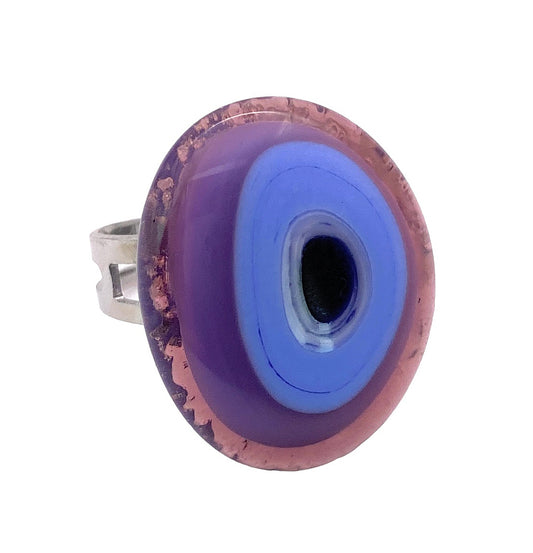 This eye-catching statement ring from Murano Passion features an abstract-shaped, large round purple and blue glass dome with concentric circles reminiscent of an eye. Complemented by a simple, adjustable metal band, this genuine Murano Glass Ring is designed to captivate attention.