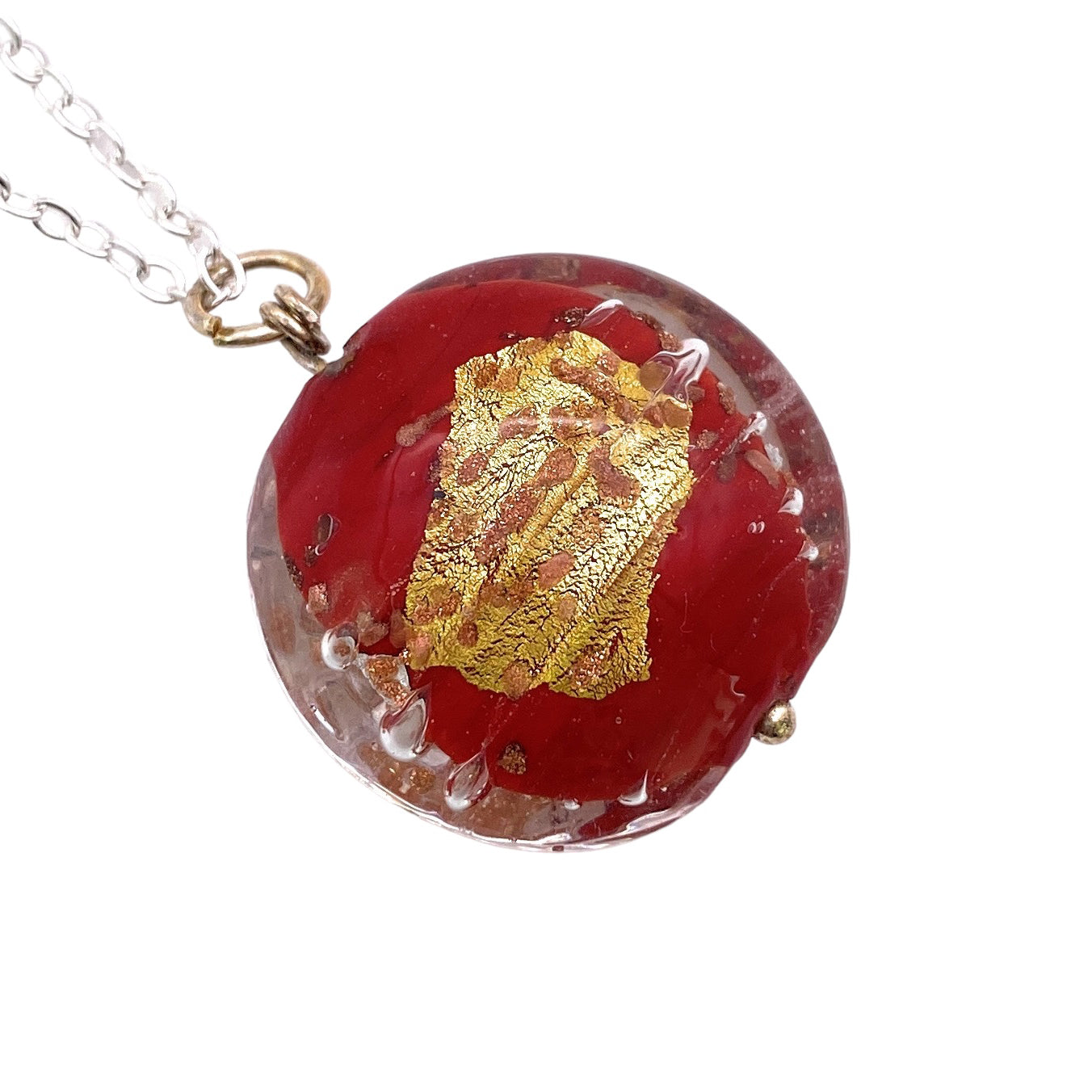 A stunning Murano Passion Glass Pendant, this 2.5cm round piece features a beautiful gold foil design set in vibrant red resin, gracefully hanging from a silver chain. This handmade glass bead pendant exemplifies exquisite craftsmanship and comes with a Certificate of Authenticity to ensure its genuine and timeless appeal.