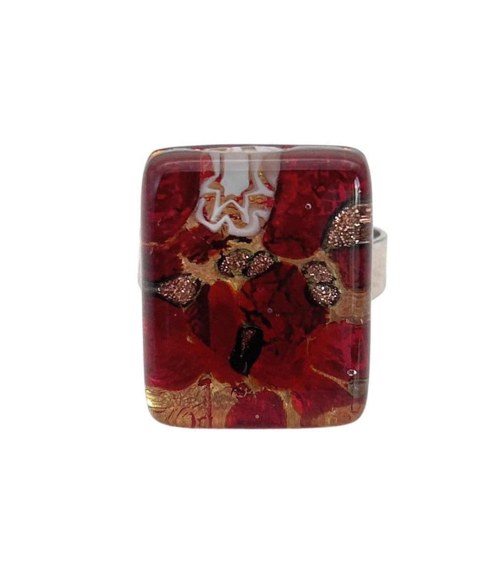 Introducing the Murano Passion Murano Glass Ring (MGR2), showcasing a striking rectangular design with a glossy red surface adorned with abstract patterns of gold, white, and black inclusions. This exquisite piece captures the essence of Venetian artistic heritage and features a silver-toned band.