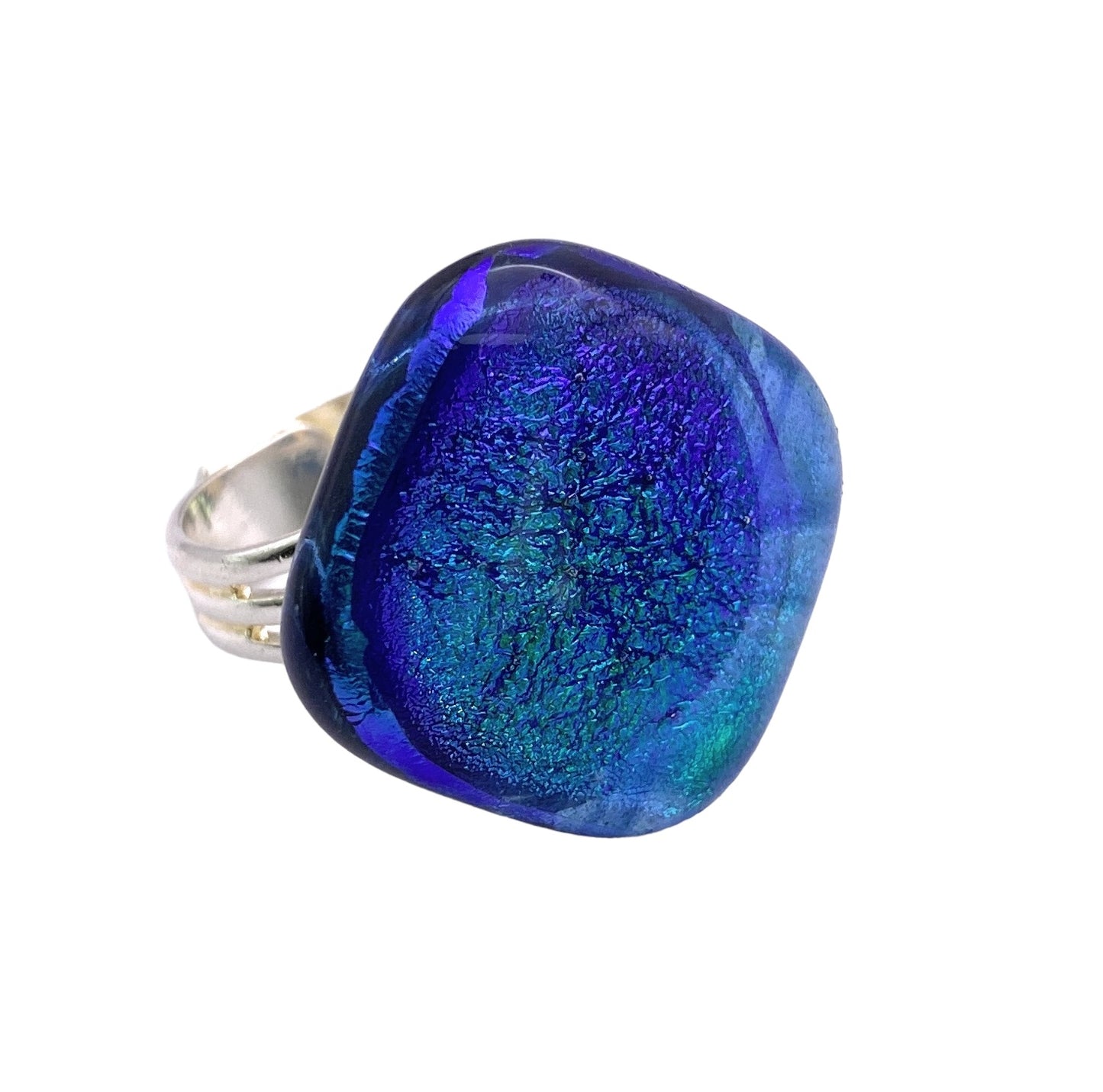 The Calon Glass Handmade Dichroic Glass Ring showcases a square blue and green dichroic glass centerpiece with a textured surface. Its smooth band is adjustable, perfectly complementing the ring's distinctive charm.