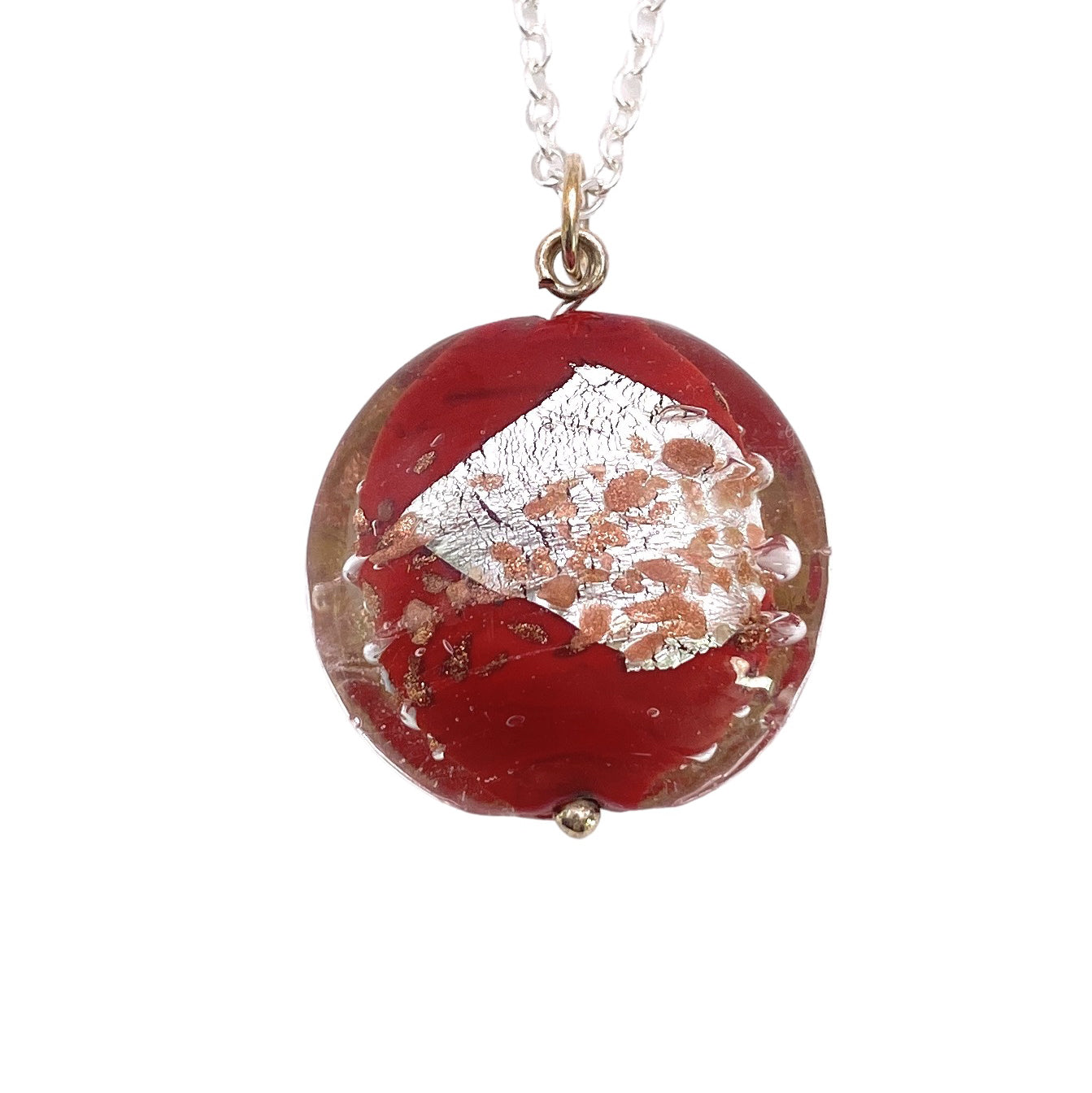 A pendant from Murano Passion, showcasing a glossy red oval design with a textured silver leaf centerpiece, elegantly suspended from a delicate chain. This handmade glass bead pendant is crafted with exquisite blown glass and measures 2.5 cm.