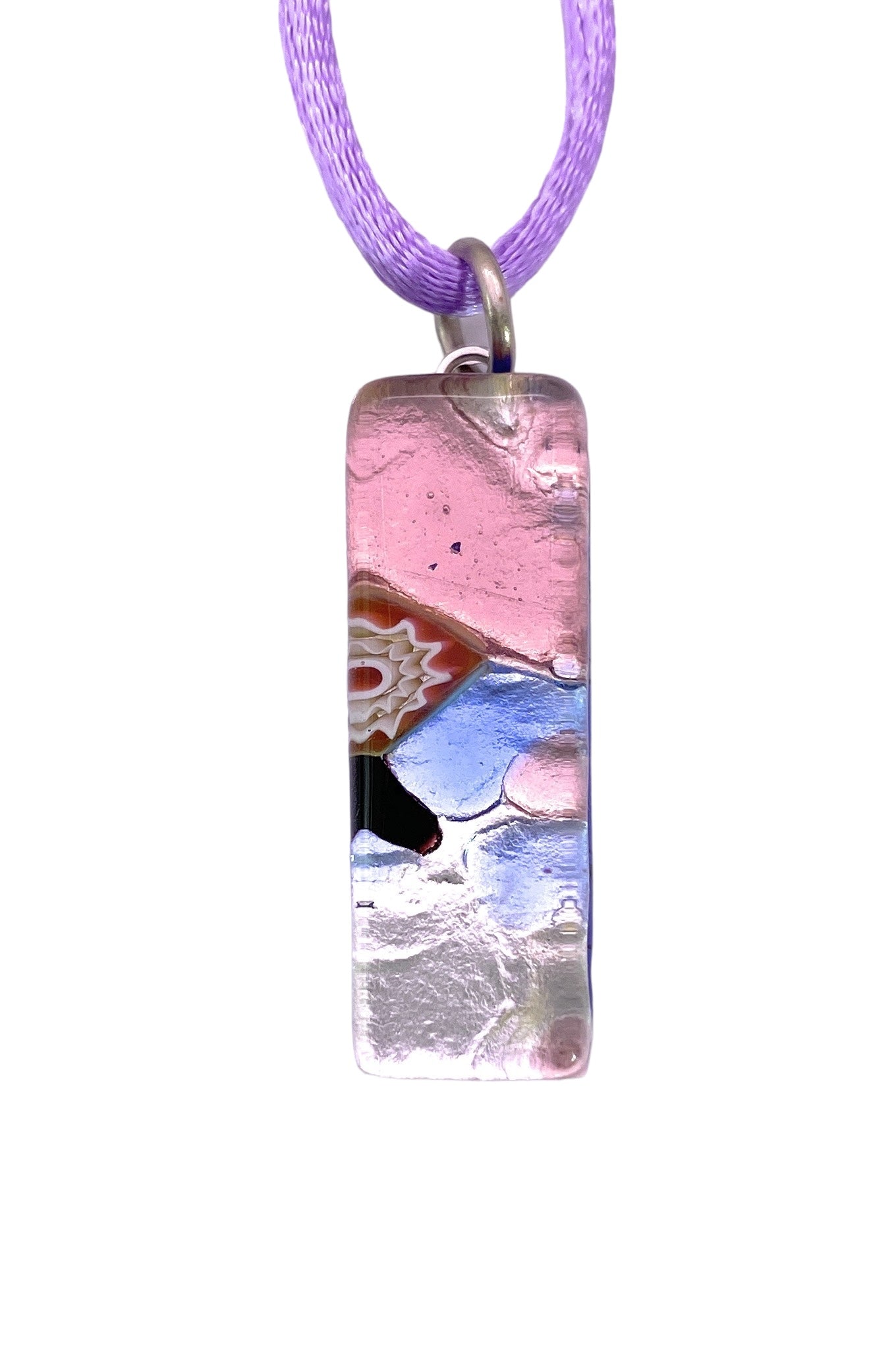 The Murano Passion Murano Glass Pendant on Silver Leaf (MGPL15) features a rectangular shape with a vibrant, abstract design in pink, black, and blue tones. It hangs elegantly from a light purple cord with an artistic layered appearance, secured by a metal loop. This unique accessory measures 3cm by 1cm and may come with a Certificate of Authenticity.