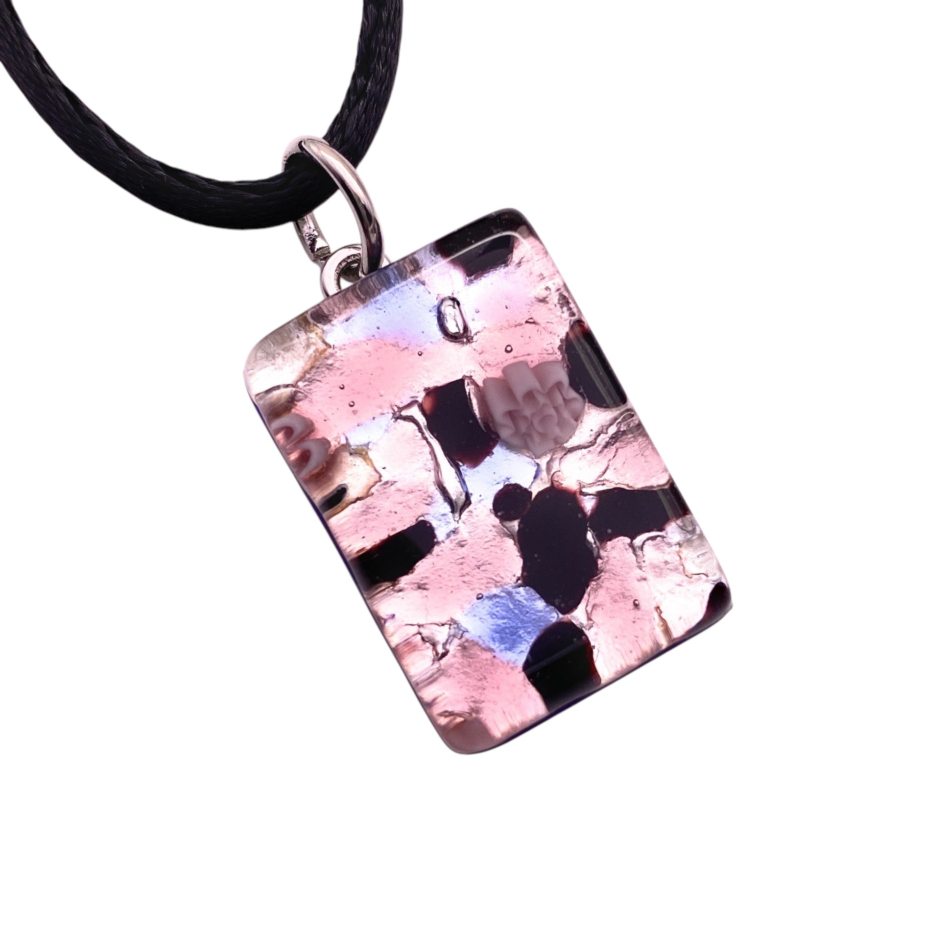 The Murano Passion MGPP10 pendant is handcrafted from Murano Glass with silver leaf, featuring a pink, black, and white abstract pattern. Hanging on a black cord, this dainty 2.5cm x 1.5cm piece has irregular shapes and a glossy finish for modern artistic appeal.