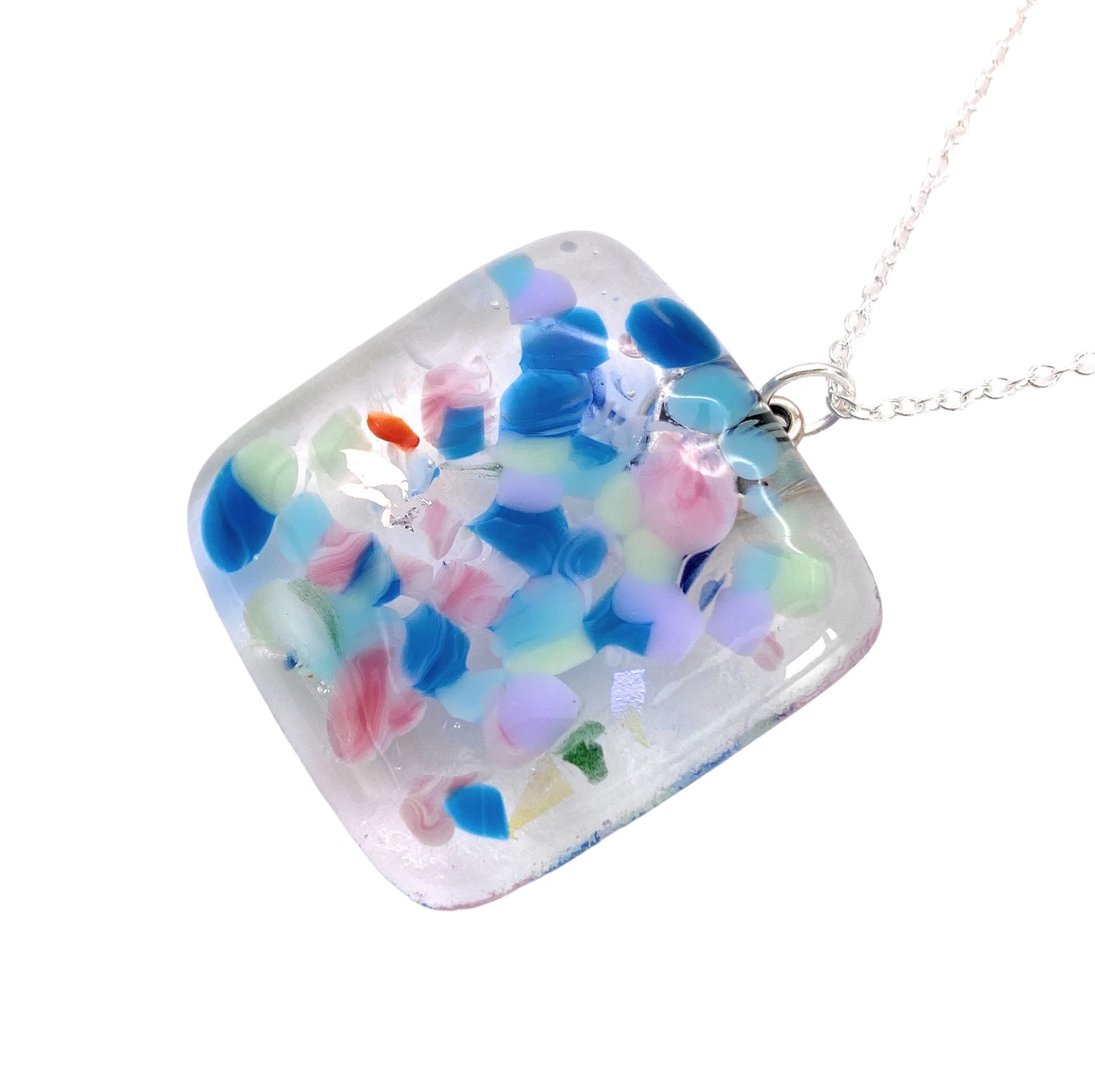 The Handmade Dichroic Glass Pendant by Calon Glass features a 3cm x 3cm square design with a vibrant rainbow mosaic of pink, blue, green, and white swirls, elegantly suspended on a silver chain.