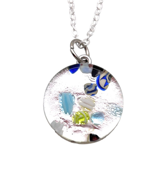 The Murano Passion Murano Glass Round Pendant made with Millefiori - 2cm (MGPV21) presents a refined round glass design suspended on a silver chain, featuring vivid abstract patterns in blue, green, and silver hues, and includes a Certificate of Authenticity.