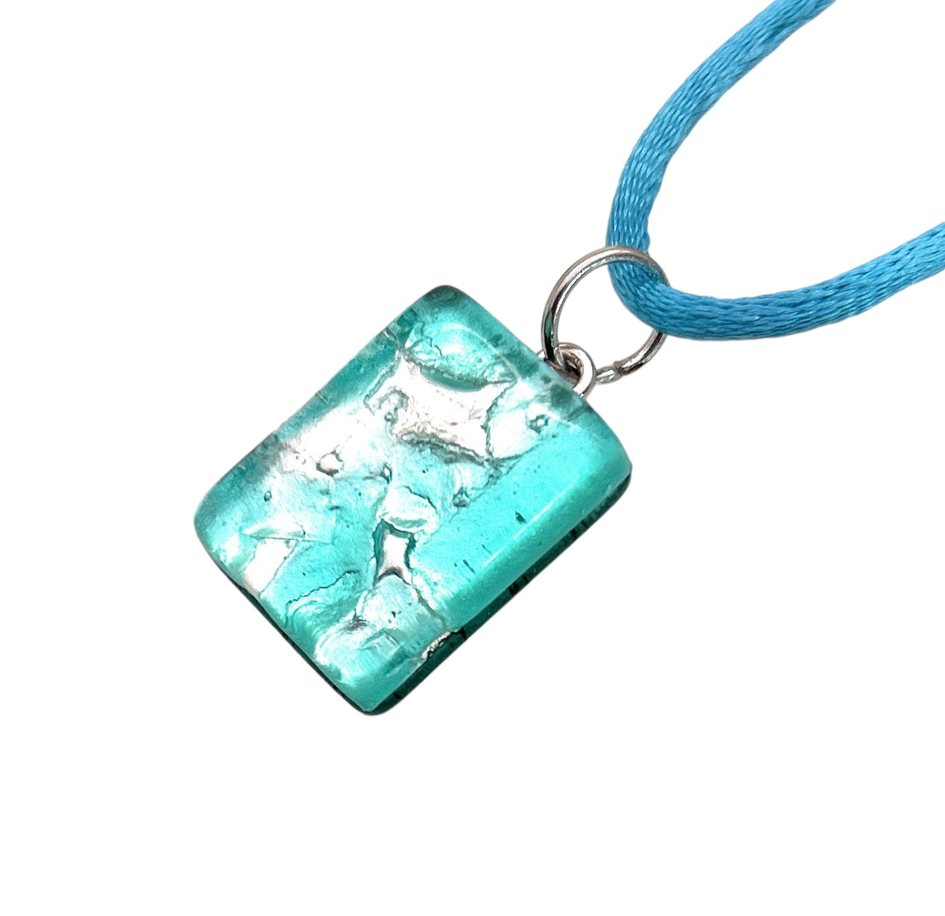 The Murano Passion Murano Glass Pendant made using Silver Leaf, a dainty 2cm x 1.5cm piece, beautifully reminiscent of exquisite Murano Glass with its turquoise hue and silver foil details, is elegantly attached to a thin blue cord.