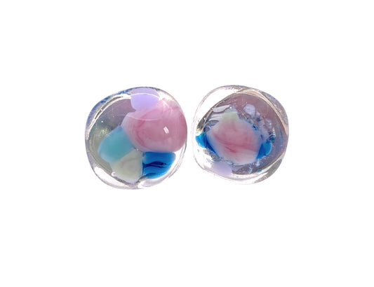 Here is a rewritten sentence incorporating the provided product data:

Close-up of two handmade glass earrings from Calon Glass, featuring oval shapes adorned with pastel-colored swirls in pink, blue, and white. These Rainbow Mosaic Glass Earrings are 1.2cm in size and have a glossy finish, resembling abstract miniature artworks—a perfect addition to unique jewelry collections.