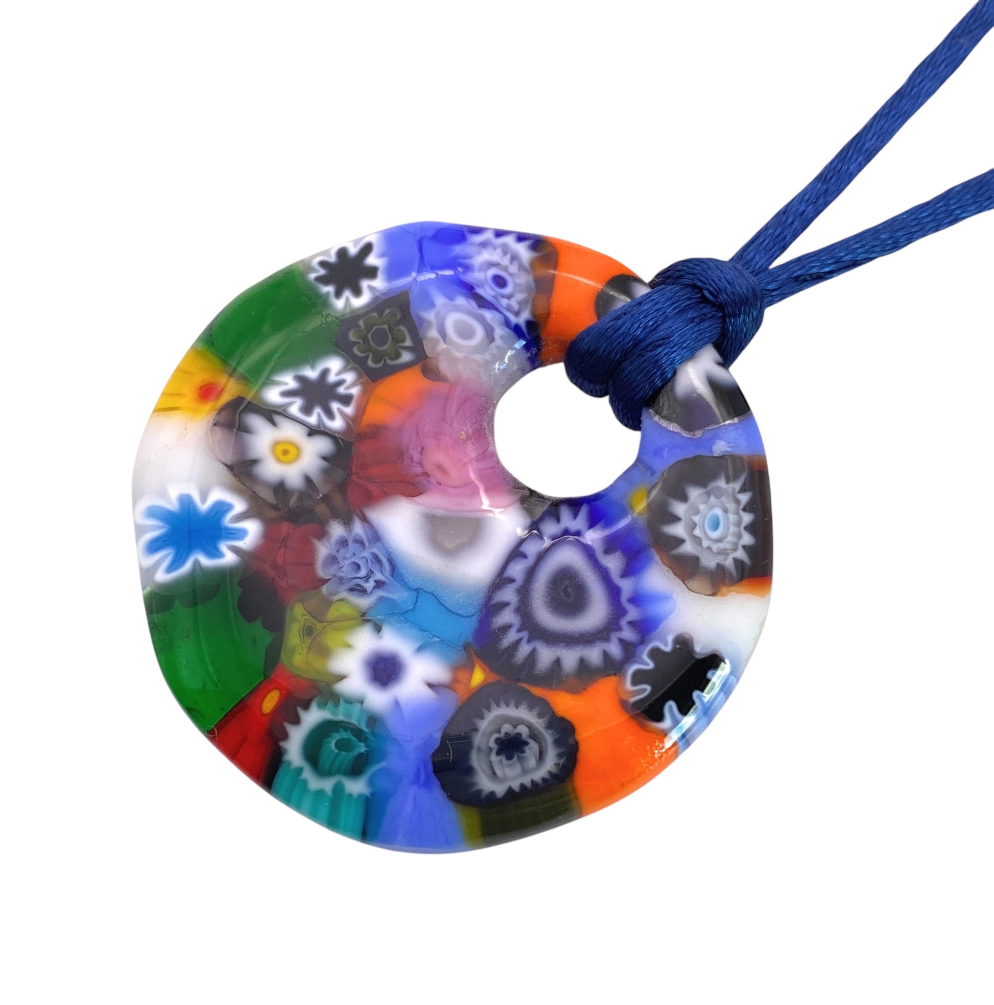 The Murano Passion Millefiori Pendant (MGPV23) features vibrant glass flowers in a spectrum of red, blue, green, and orange hues on a blue cord. This exquisite Murano Glass Pendant showcases intricate abstract motifs in a stunning circular design that reflects the artistry of Murano Glass Jewellery.