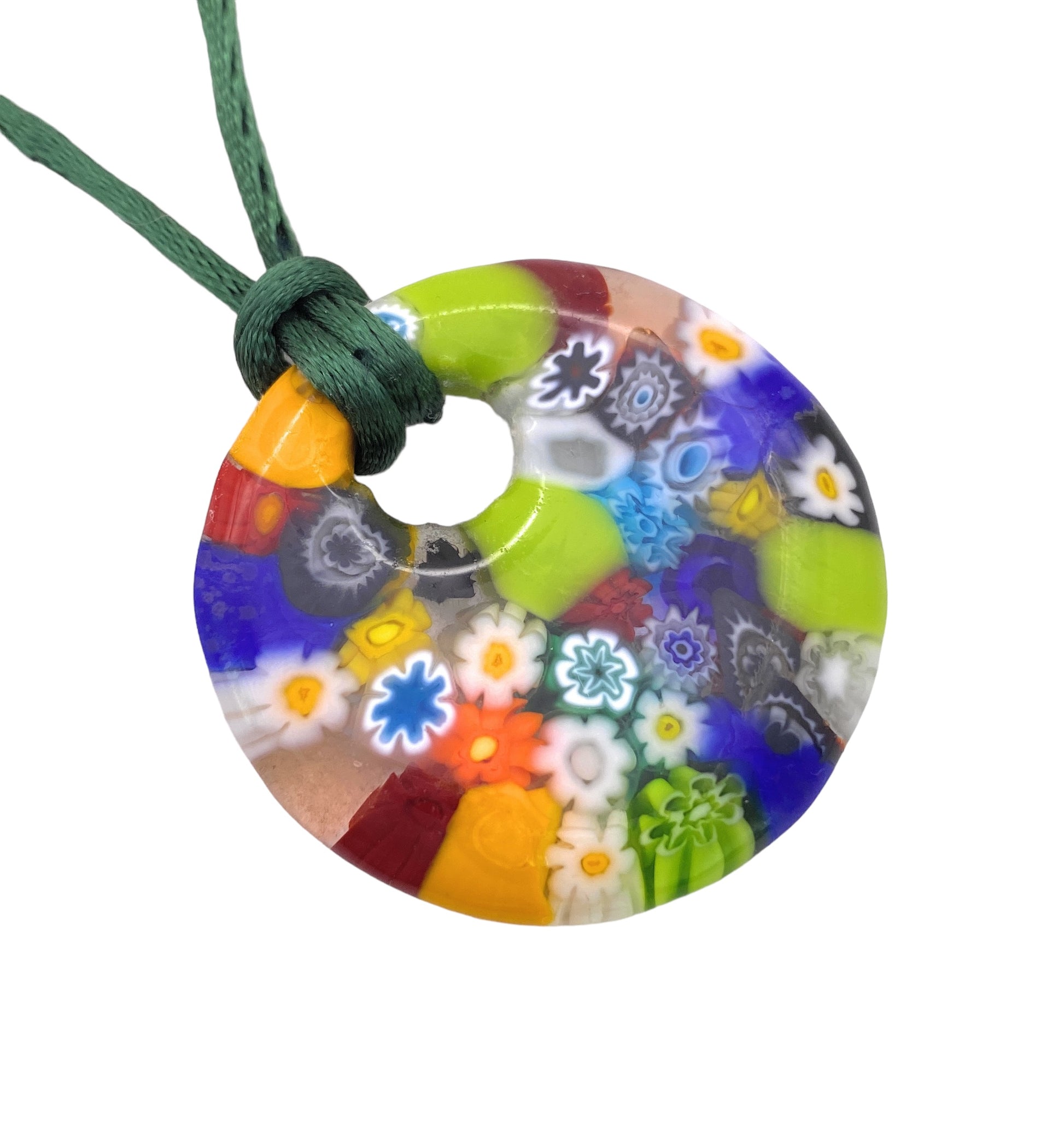 This Murano Passion glass pendant, named "Millefiori Flower Pendant - 4cm," is an authentic piece that boasts a vibrant circular design with intricate floral patterns. Featuring a green cord, it beautifully displays a millefiori pattern of blue, yellow, red, orange, and green flowers set against a clear background.