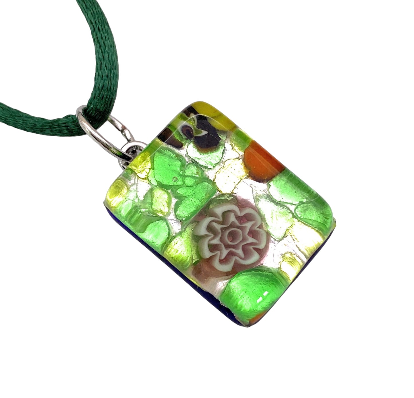 The Murano Passion MGPP17 pendant features a rectangular design with a vibrant floral pattern, highlighted by green, yellow, and orange hues around a central flower motif. Suspended on an elegant green string, this 2cm x 1.5cm Millefiori Flowers on Silver Leaf piece is an exquisite example of Murano Glass Jewellery and includes a Certificate of Authenticity.