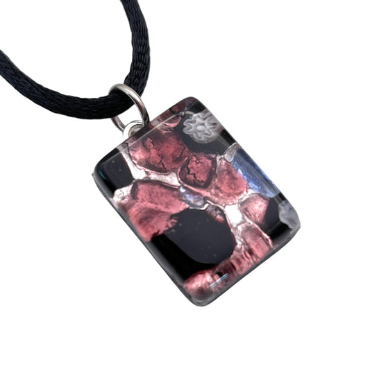 Introducing the Murano Glass Pendant, Millefiori Flower on Silver Leaf by Murano Passion. This elegant piece measures 2cm by 1.5cm and features black glass adorned with pink and white marbled patterns, attached to a black cord via a silver loop. Its intricate design showcases abstract, organic shapes and comes complete with a Certificate of Authenticity.