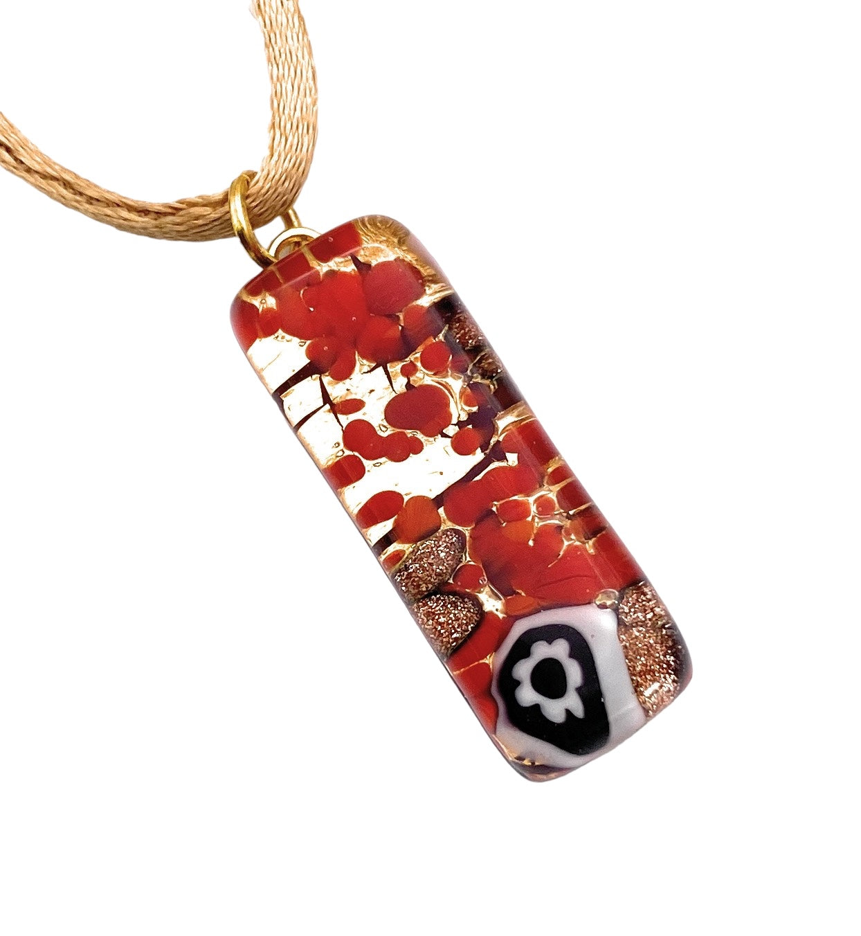 The Murano Passion Murano Glass Pendant (MGPL12) features a striking rectangular design measuring 3cm by 1cm. It showcases a vibrant blend of red, orange, and metallic gold patterns, elegantly suspended from a gold cord. The piece is beautifully accentuated with a small black and white floral Millefiori design at the bottom right, capturing the essence of exquisite Murano Glass Jewellery.