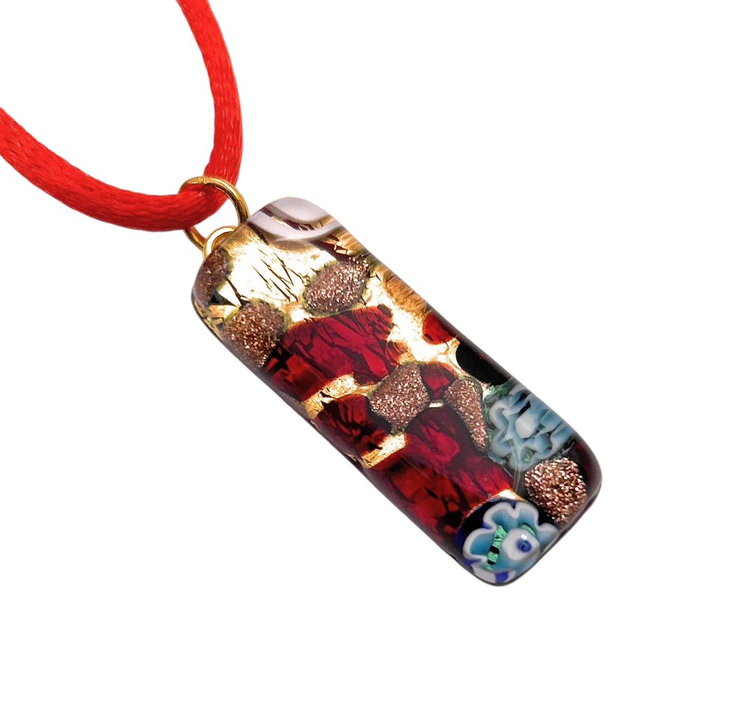 The Murano Passion MGPL3 pendant, made using Millefiori Flowers on Gold Leaf, measures 3cm x 1cm and showcases a captivating mix of red, blue, and metallic tones in an abstract design. It has a glossy finish and hangs elegantly from a bright red cord. For added assurance, it comes with a Certificate of Authenticity.