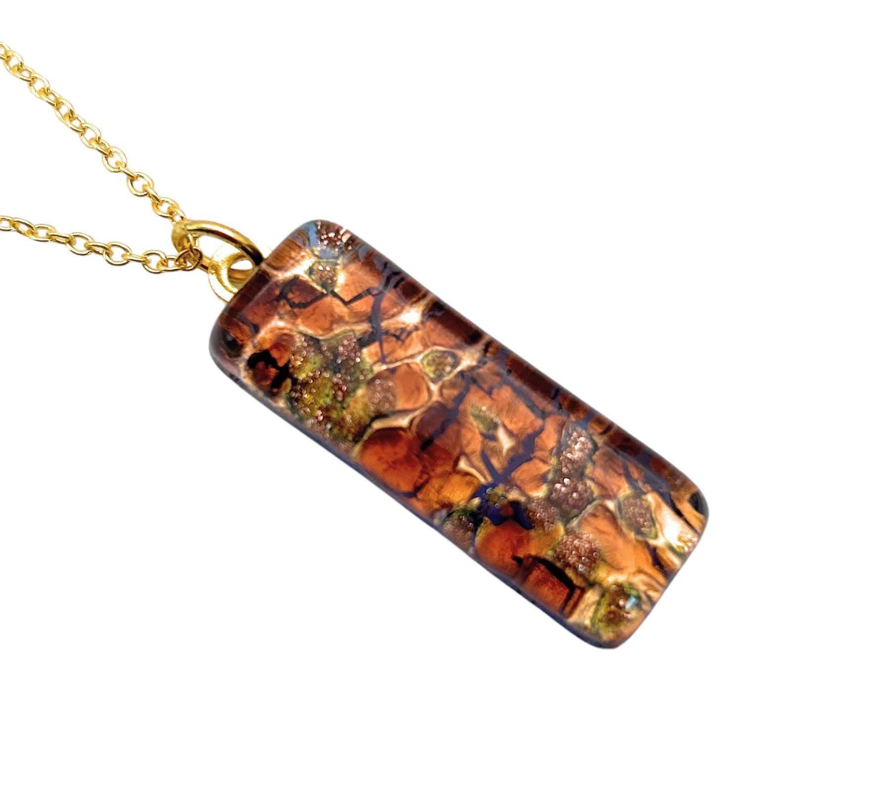 The Murano Passion Murano Glass Pendant, crafted with gold leaf in a 3cm x 1cm rectangular shape (MGPL13), showcases a cracked, earthy pattern in brown, green, and orange tones. It hangs elegantly from a gold chain and resembles mosaic or abstract art. The pendant is accompanied by a Certificate of Authenticity.